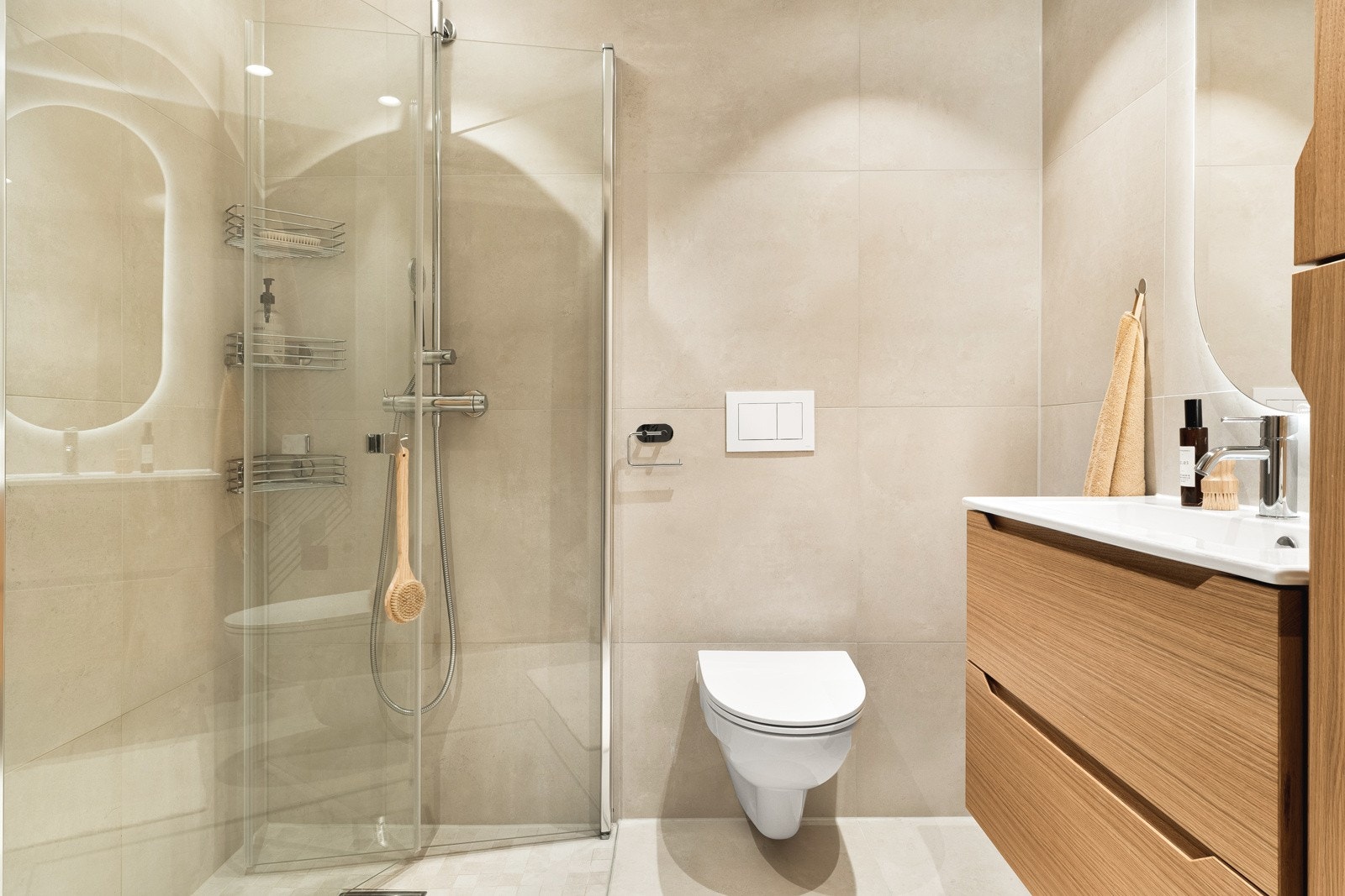 Leiligheten har et strøkent og tidløst bad. Badet ble i 2023 oppgradert med storformat fliser på gulv og vegger i kombinasjon med mosaikkfliser i dusjsonen. Galleribilde