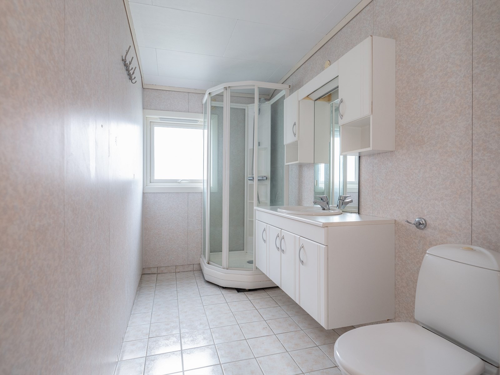 Lyst og romslig bad av eldre standard i 2. etasje. Badet har varmekabler i gulv, gulvmontert toalett og dusjkabinett, samt servantinnredning. Galleribilde