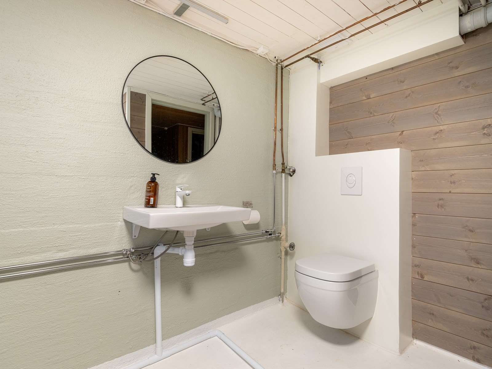 Det er i følge eier mikrosement på gulv. Øvrige overflater består av malt betong og pen panel på vegger, samt malt panel i tak. Galleribilde