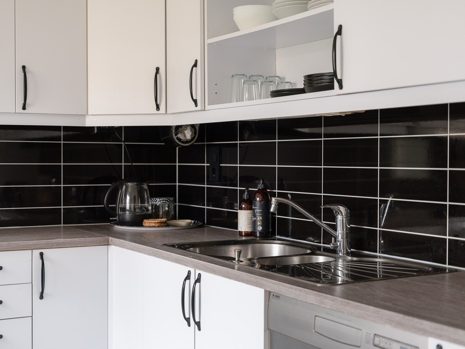 Laminat benkeplate med gode arbeidsflater og nedfelt benkebeslag. Fuktbestandige plater i flisimitasjon på vegg mellom over og underskap. Galleribilde