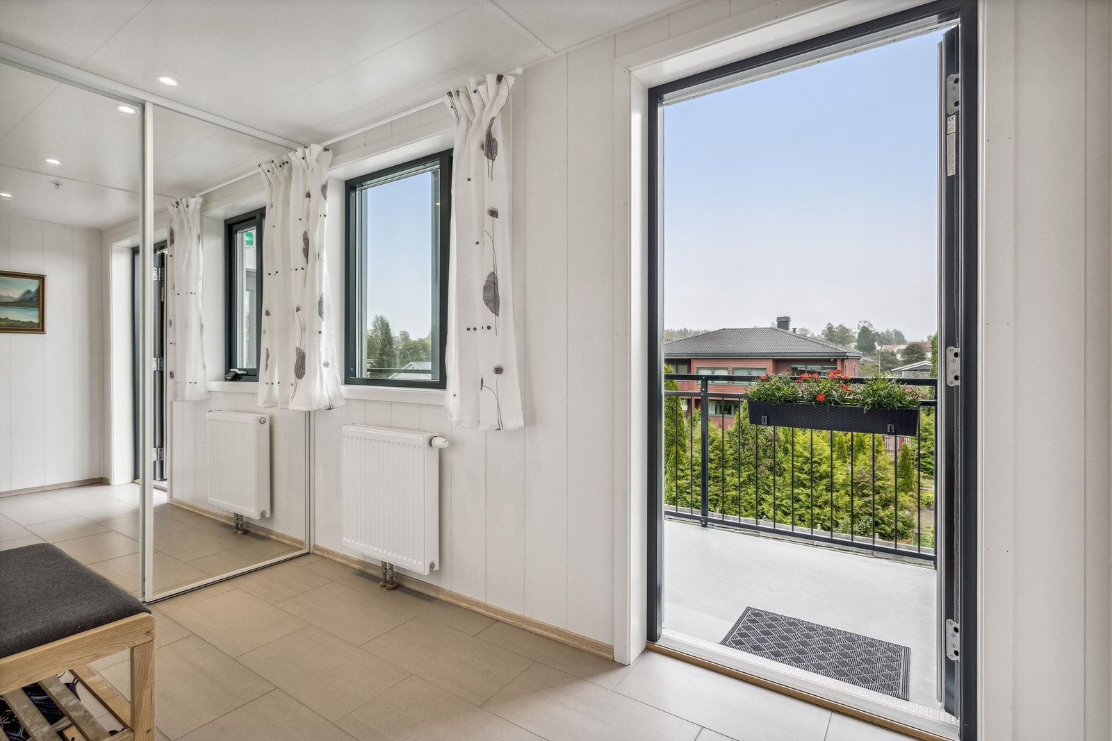 Entré med hvitmalt plater på veggene og lyse fliser på gulvet. Entréen har etablert en skyvedørsgarderobe med speildører hvor man kan henge fra seg yttertøyet. Varmekabler i gulv! Galleribilde