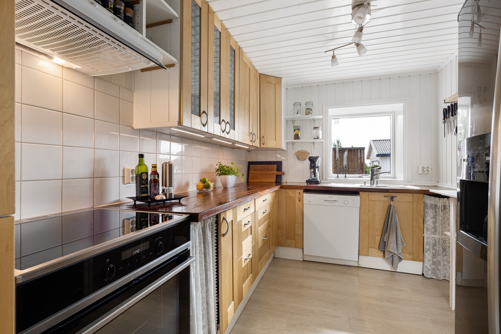 Innredningen er trefarget med profilerte fronter, vitrineskap og benkeplate i heltre med nedfelt oppvaskkum. Galleribilde