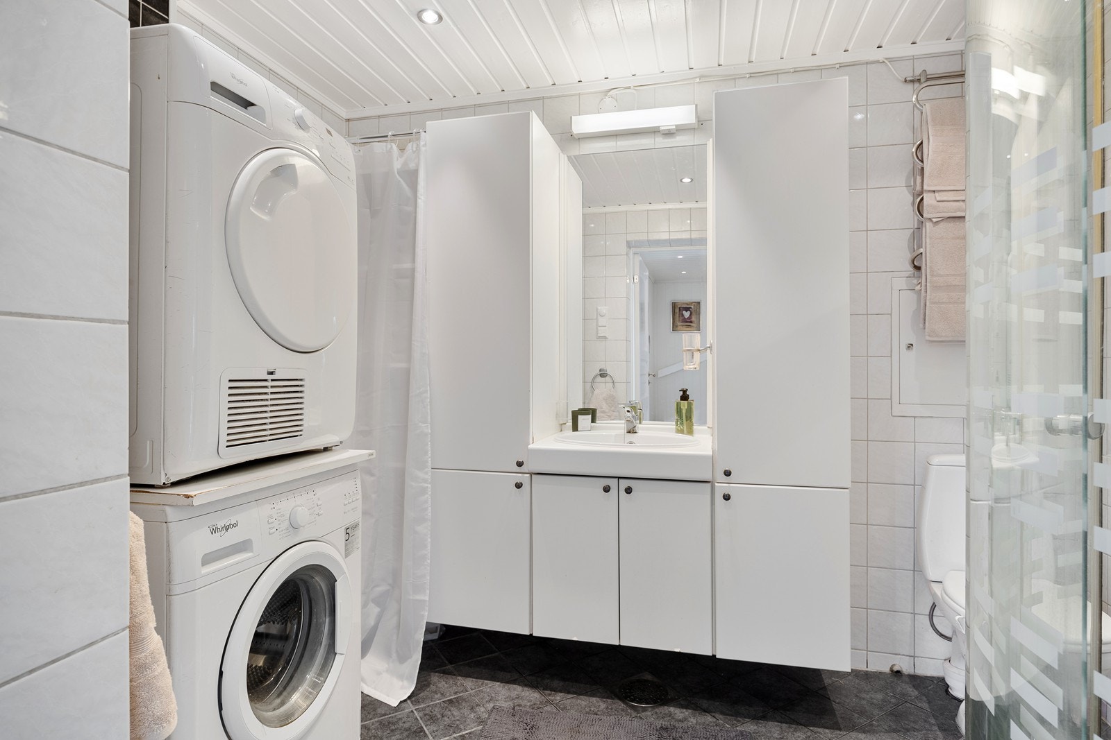 Badet gir et pent inntrykk med flislagte overflater, gulvvarme, downlights og elektrisk styrt vifte. Galleribilde