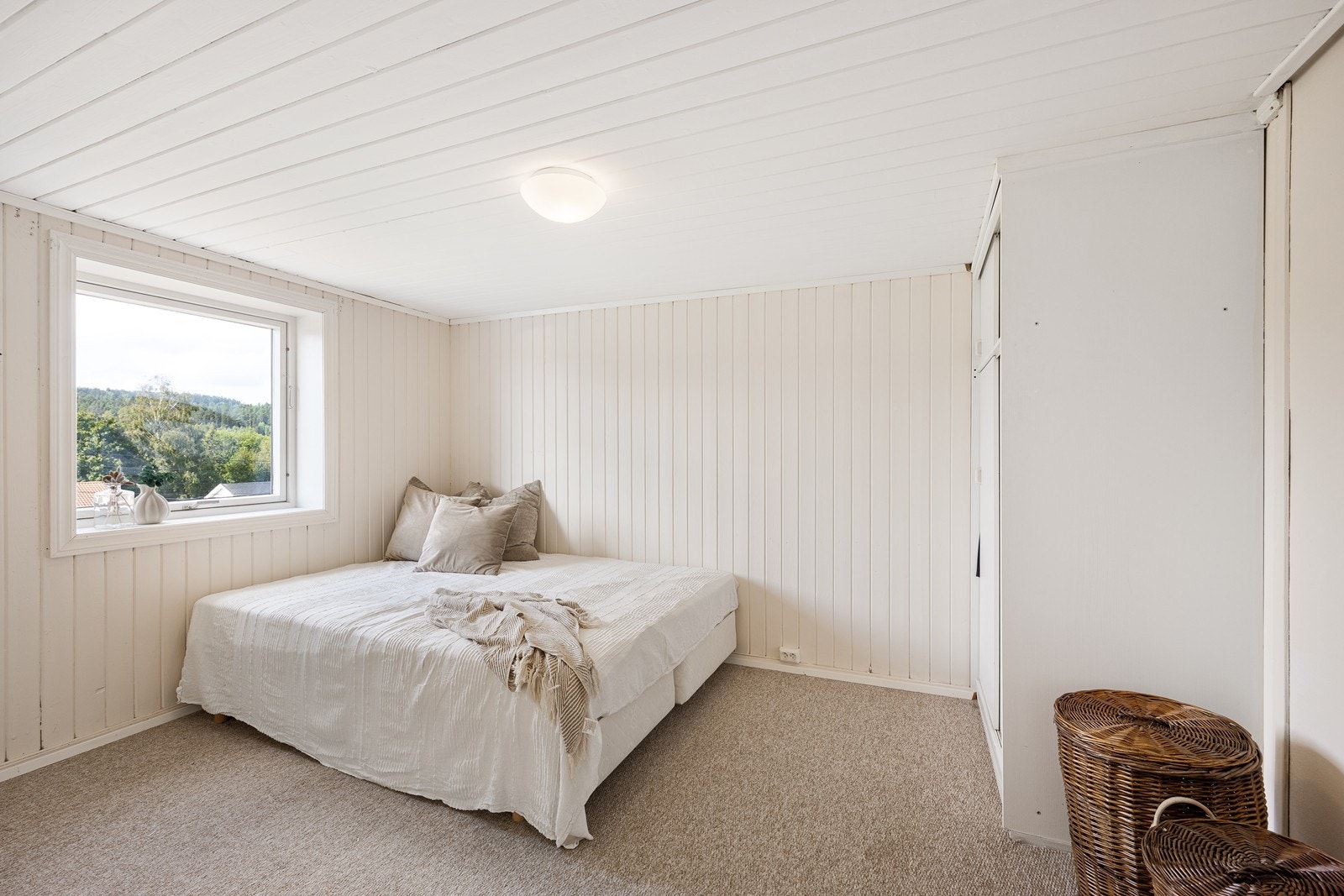 Det ene rommet har teppegulv, dus farge på veggpanel, hvit garderobeløsning og plass til dobbeltseng. Galleribilde