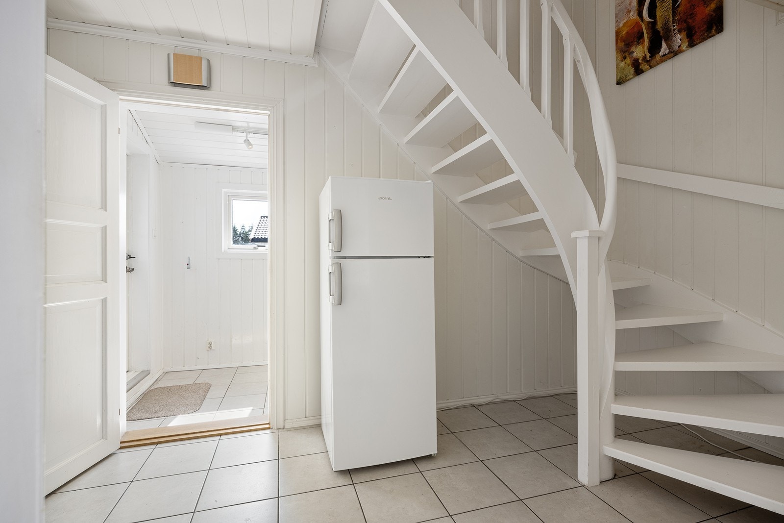 Det er videre adkomst til en gang i samme stil med hvitmalt trapp til etasjen over. Galleribilde