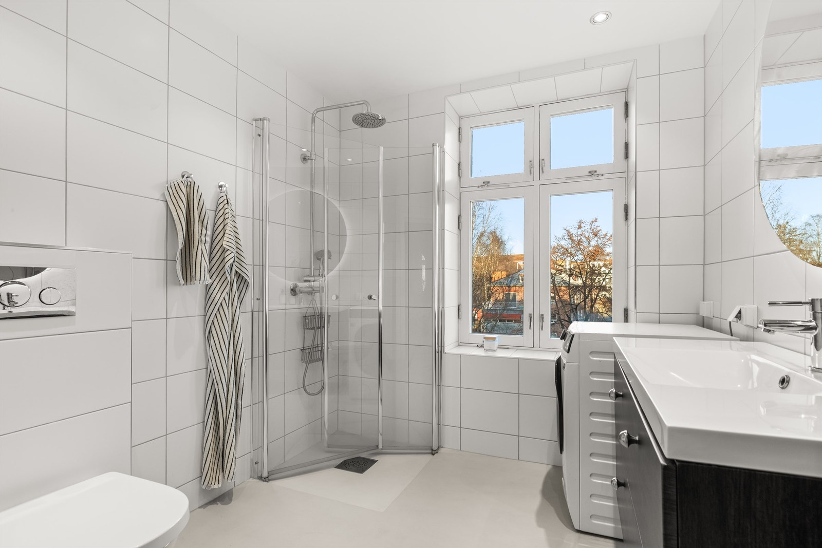 Badet har flislagte vegger og gulv med microsement og gulvvarme. Her har du et praktisk dusjhjørne med innfellbare dører i glass og regndusj. Galleribilde