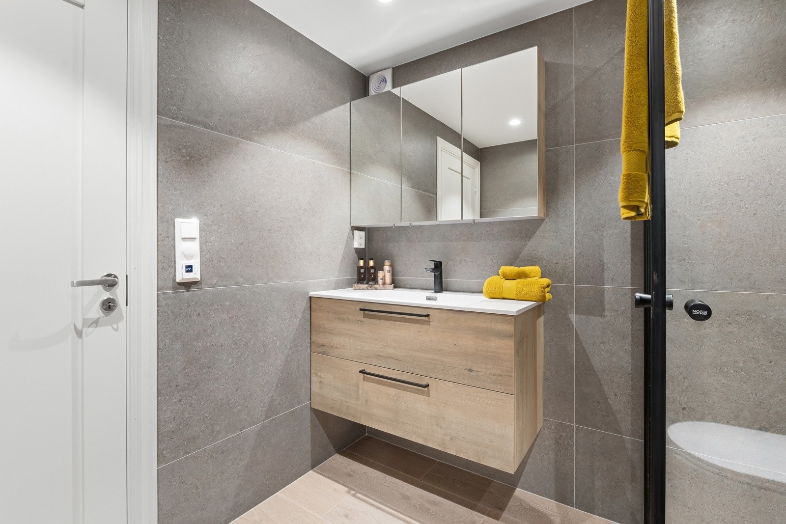 Badet har tidløse fliser og er innredet med servantskap, dusjhjørne og vegghengt wc. Galleribilde