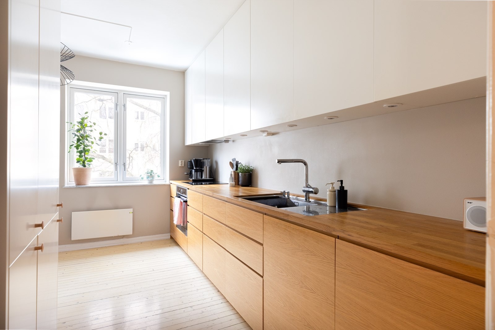 Kjøkkeninnredning med finérte fronter, benkeplate i tre, oppvaskkum i stål med avrenningsfelt. Videre er det integrerte hvitevarer i form av induksjonstopp, stekeovn, kombiskap og oppvaskmaskin. Galleribilde