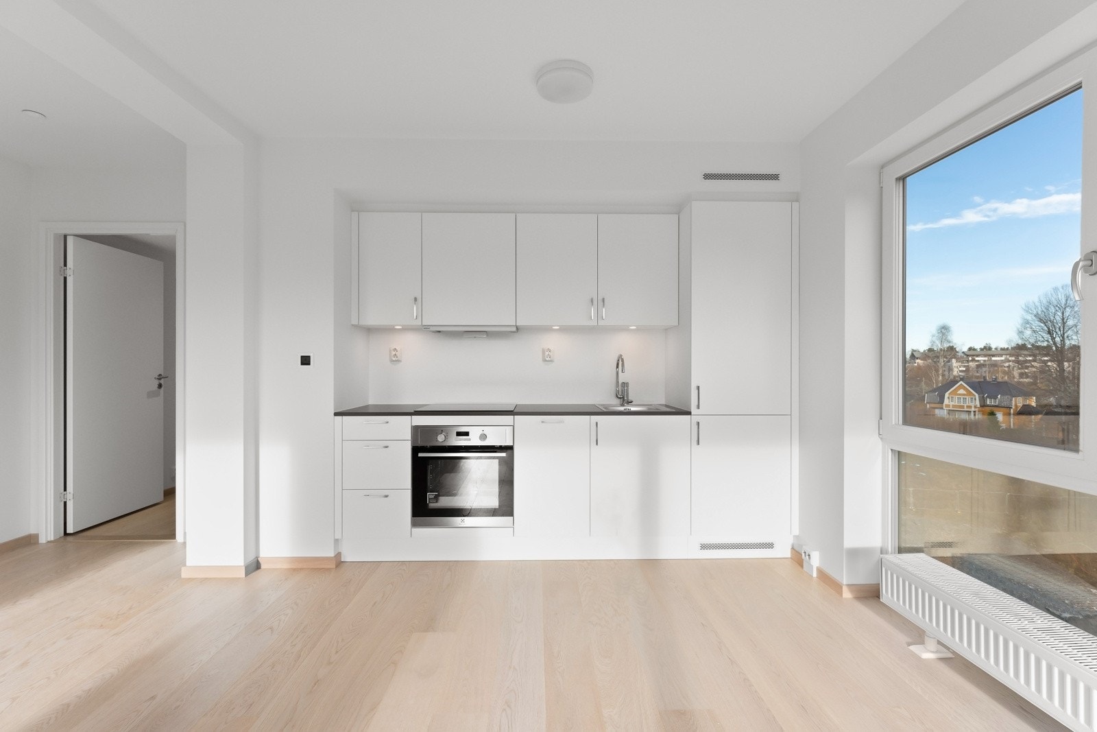 Lekkert kjøkken i åpen løsning mot stue, med integrerte hvitevarer Galleribilde