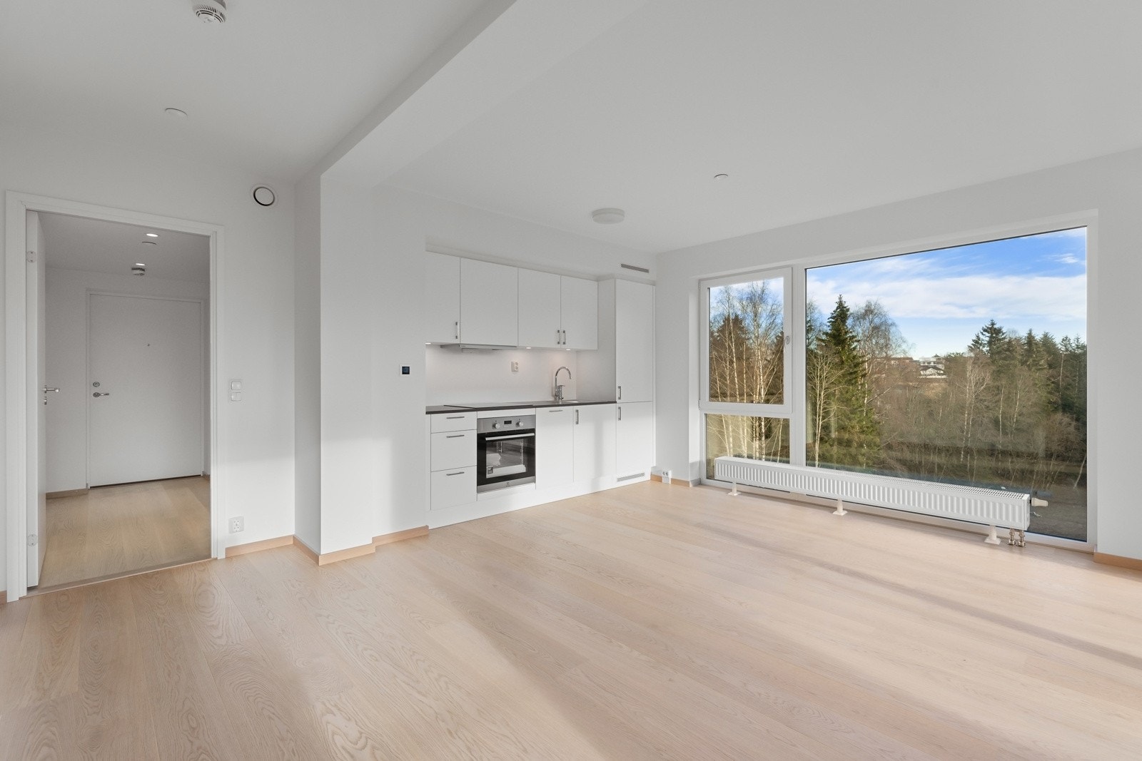 Lekkert kjøkken i åpen løsning mot stue, med integrerte hvitevarer Galleribilde