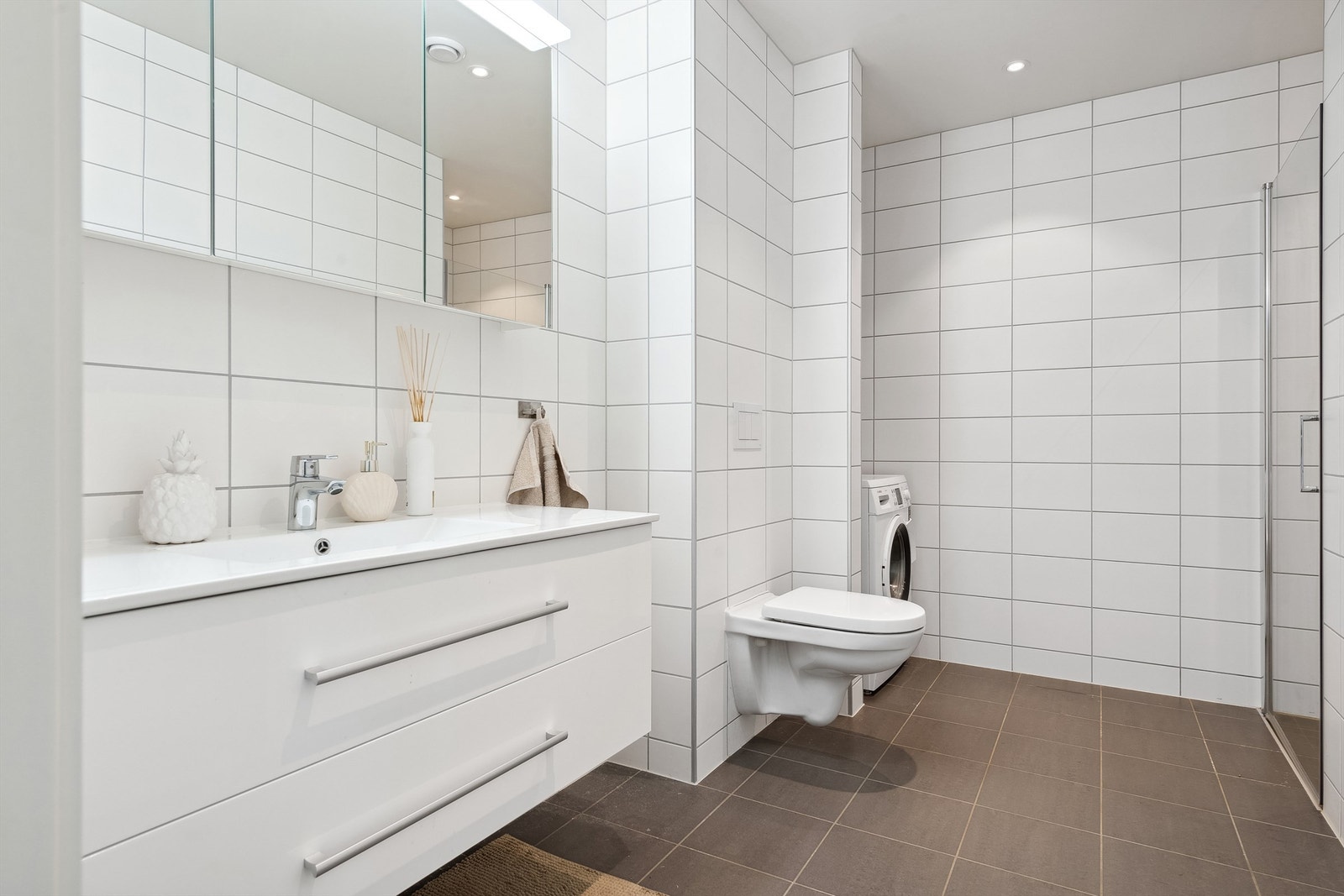 Utstyrt med en klassisk vegghengt servant med underskap som gir praktisk oppbevaringsplass, Speilskap med lys samt dusjvegger. Galleribilde