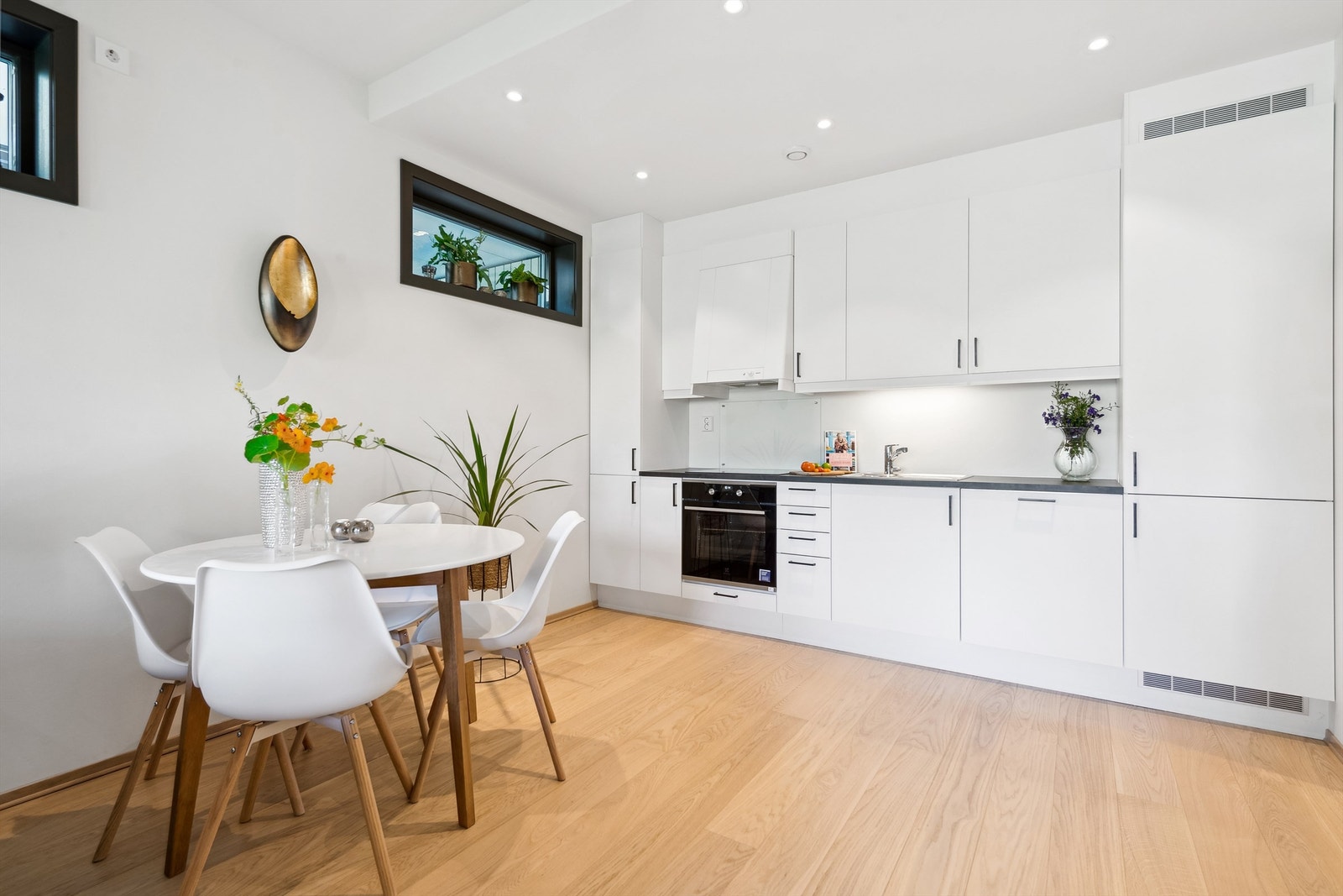 Lyst og moderne kjøkken med en innredning med laminerte skrog og glatte fronter. Laminert benkeplate med integrert kjøkken kum. Galleribilde