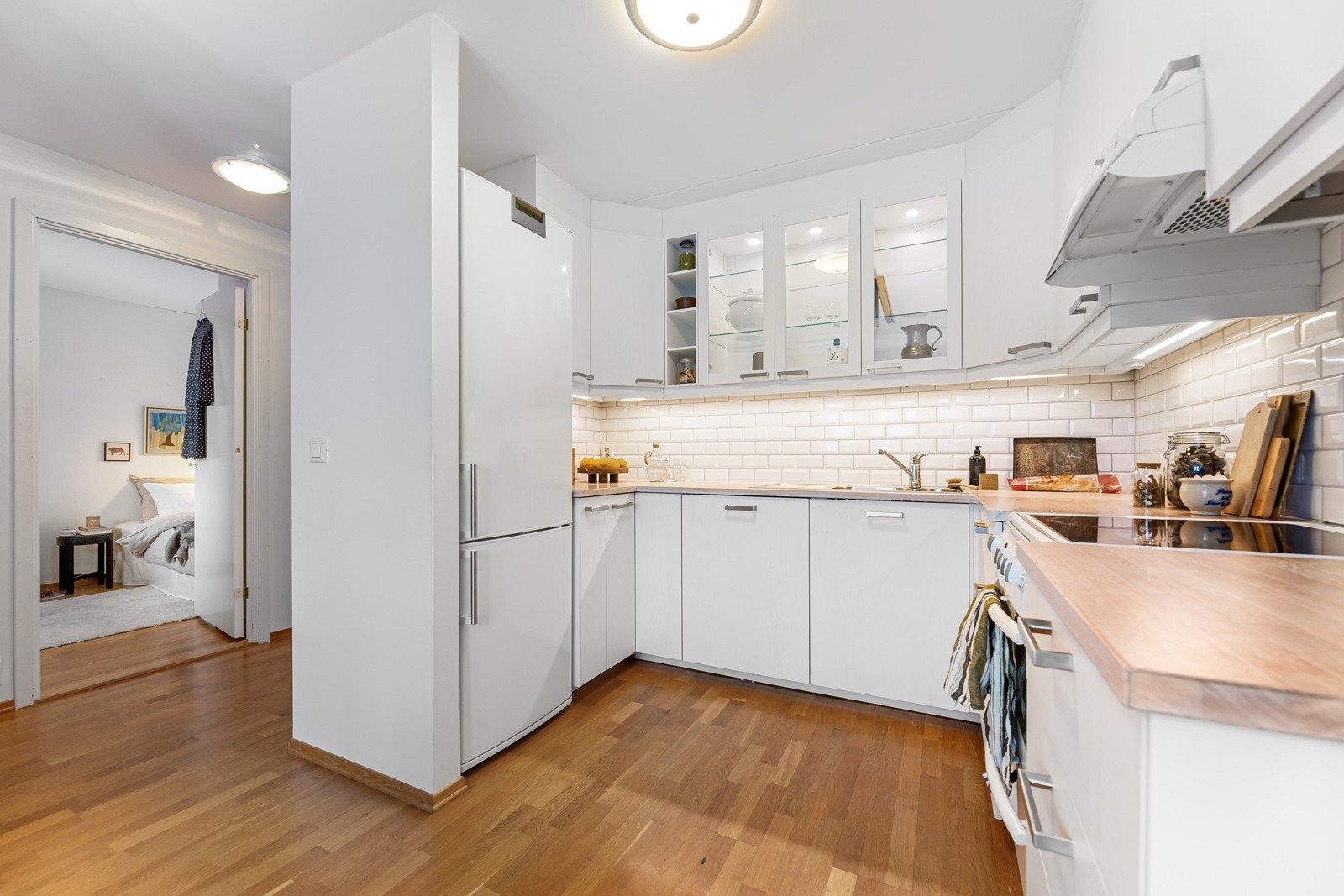 Kjøkken med glatte fronter, benkeplate av heltre, frittstående kjøl- og fryseskap og integrert oppvaskmaskin. Galleribilde