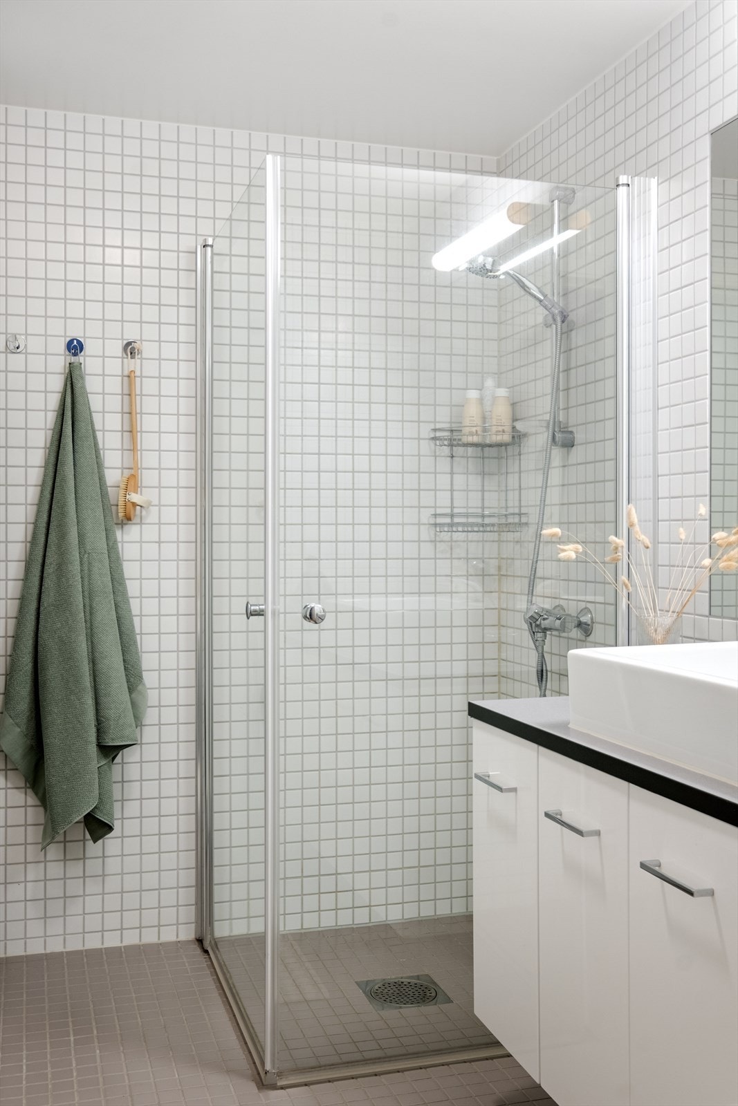 Baderommet er innredet med vegghengt klosett, servant nedfelt i innredning og dusjhjørne med svingbare glassdører. Galleribilde