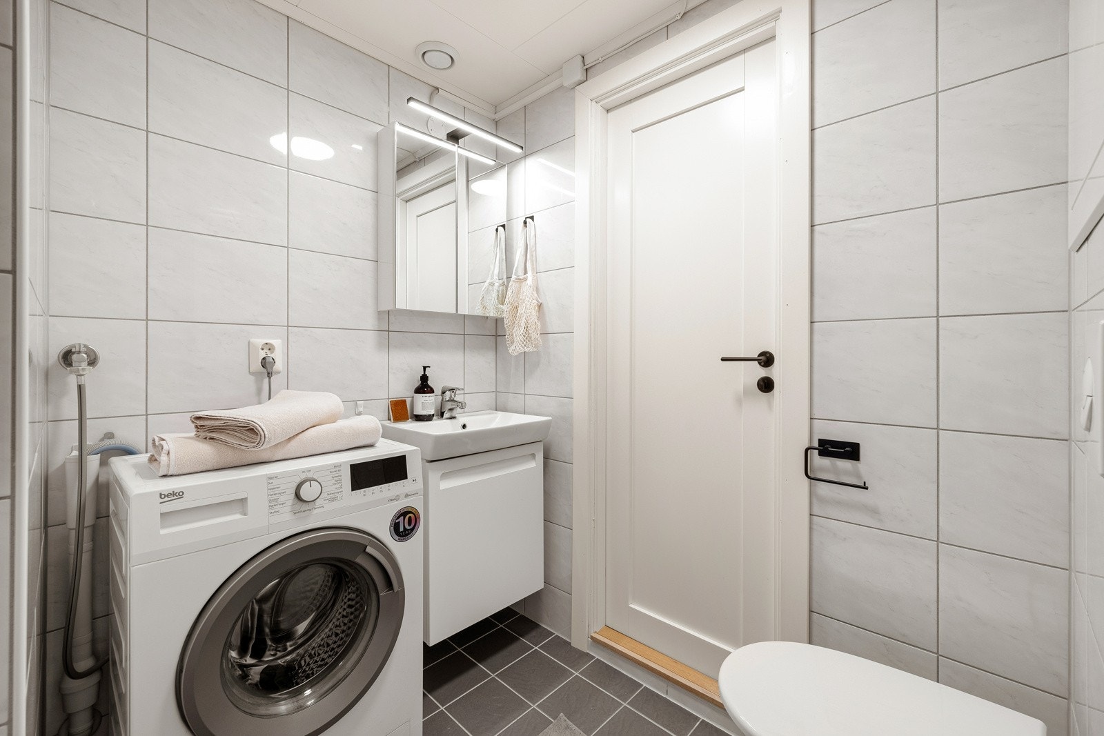 Badet i leiligheten er helfliset med lyse fliser på vegger og mørke fliser med varmekabler på gulvet. Badet måler 2,8 kvm og eier opplyser om at det ble oppusset i 2015 i regi av borettslaget. Galleribilde