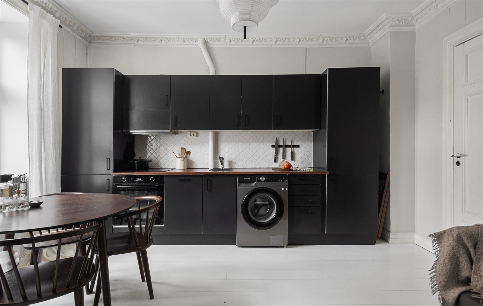 Lekkert kjøkken fra HTH med innredning bestående av skap med glatte fronter, laminat benkeplate, samt fliser og belysning under overskap. Galleribilde