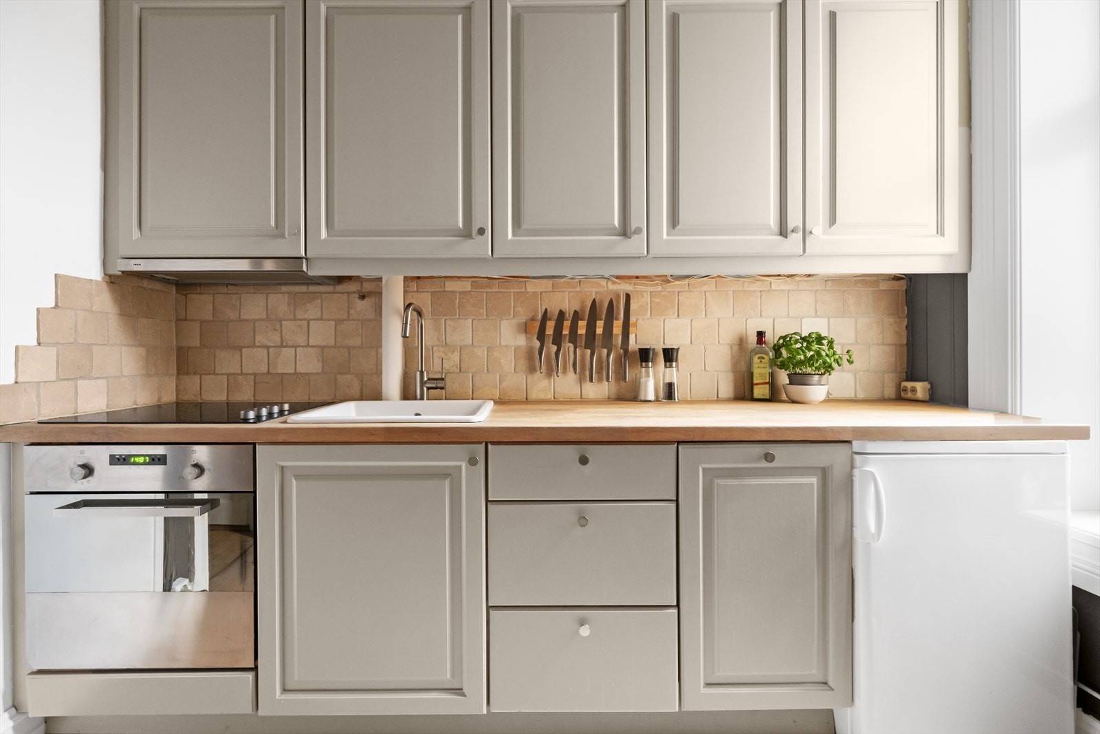 Profilerte malte fronter, benkeplate i tre med nedfelt kum i keramikk og ventilator tilsluttet kanal. Integrert platetopp, stekeovn og oppvaskmaskin. Galleribilde