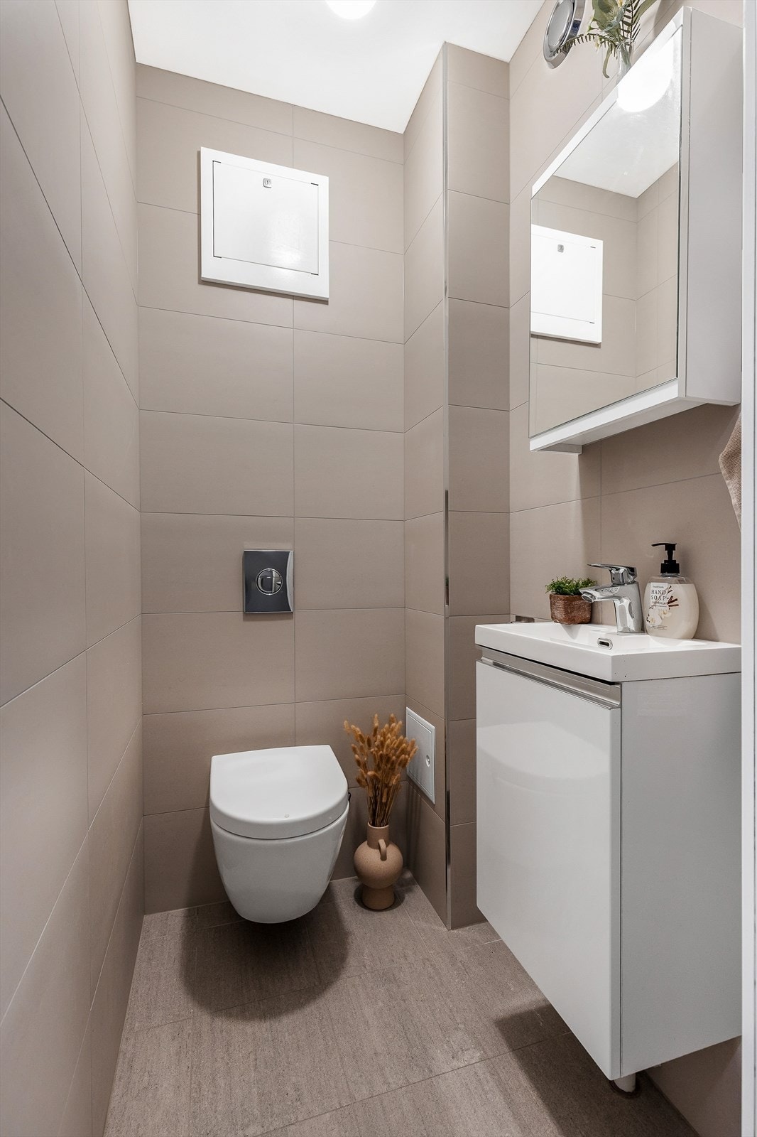 Videre er boligens toalett avholdt i et delikat, separat toalettrom, som er innredet med vegghengt klosett og servantskap med nedfelt servant og overhengt speil. Galleribilde