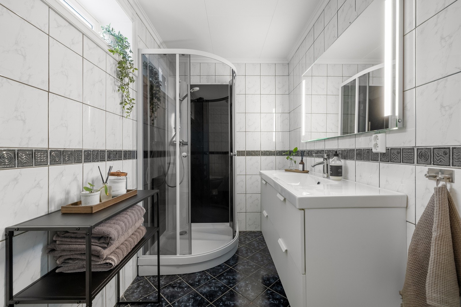 Her er det innredet med vegghengt servantinnredning, speil med sidelys, dusjkabinett og gulvstående toalett. Galleribilde