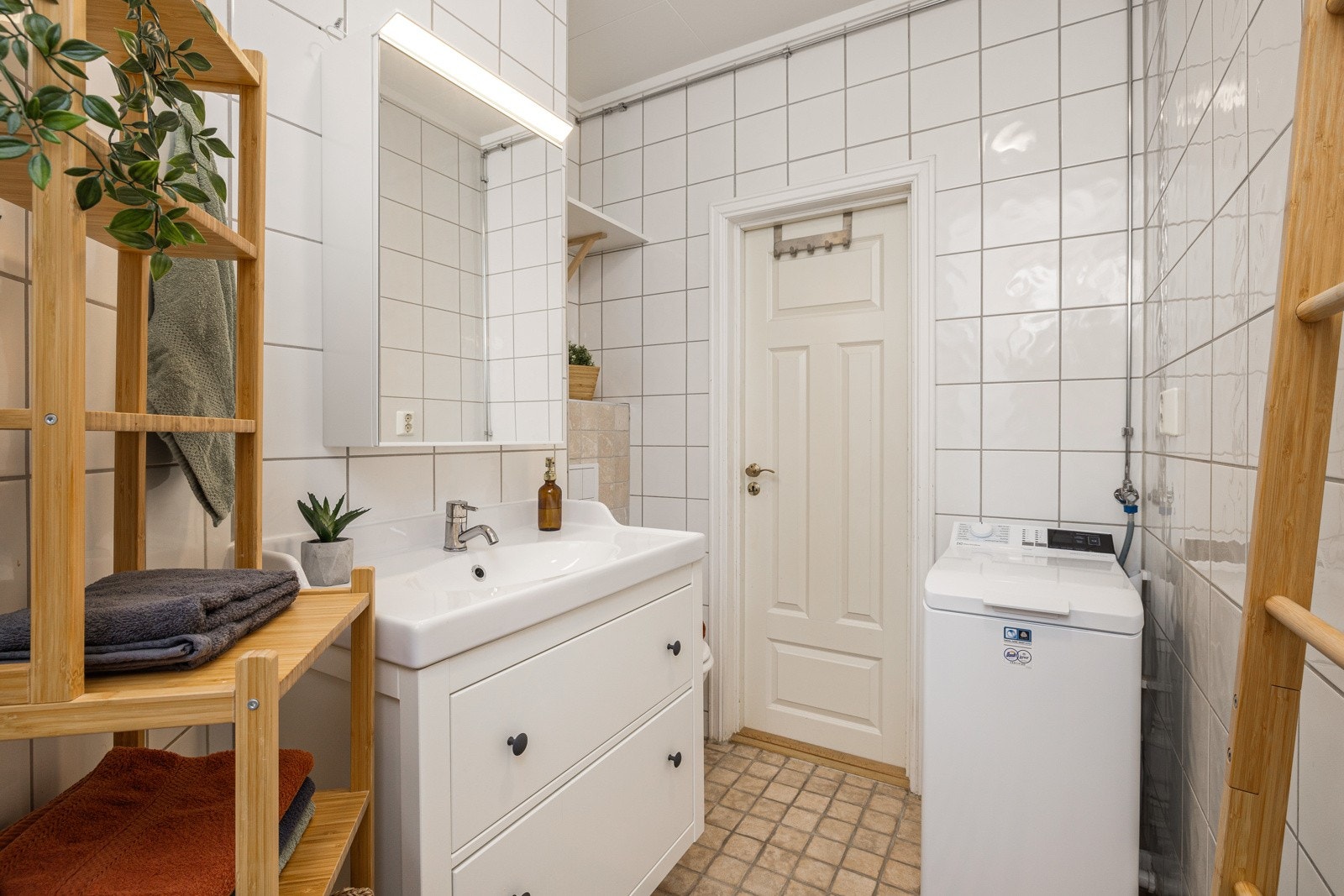 Badet er innredet med servantinnredning, vaskemaskin, vegghengt toalett og dusjhjørne. Galleribilde