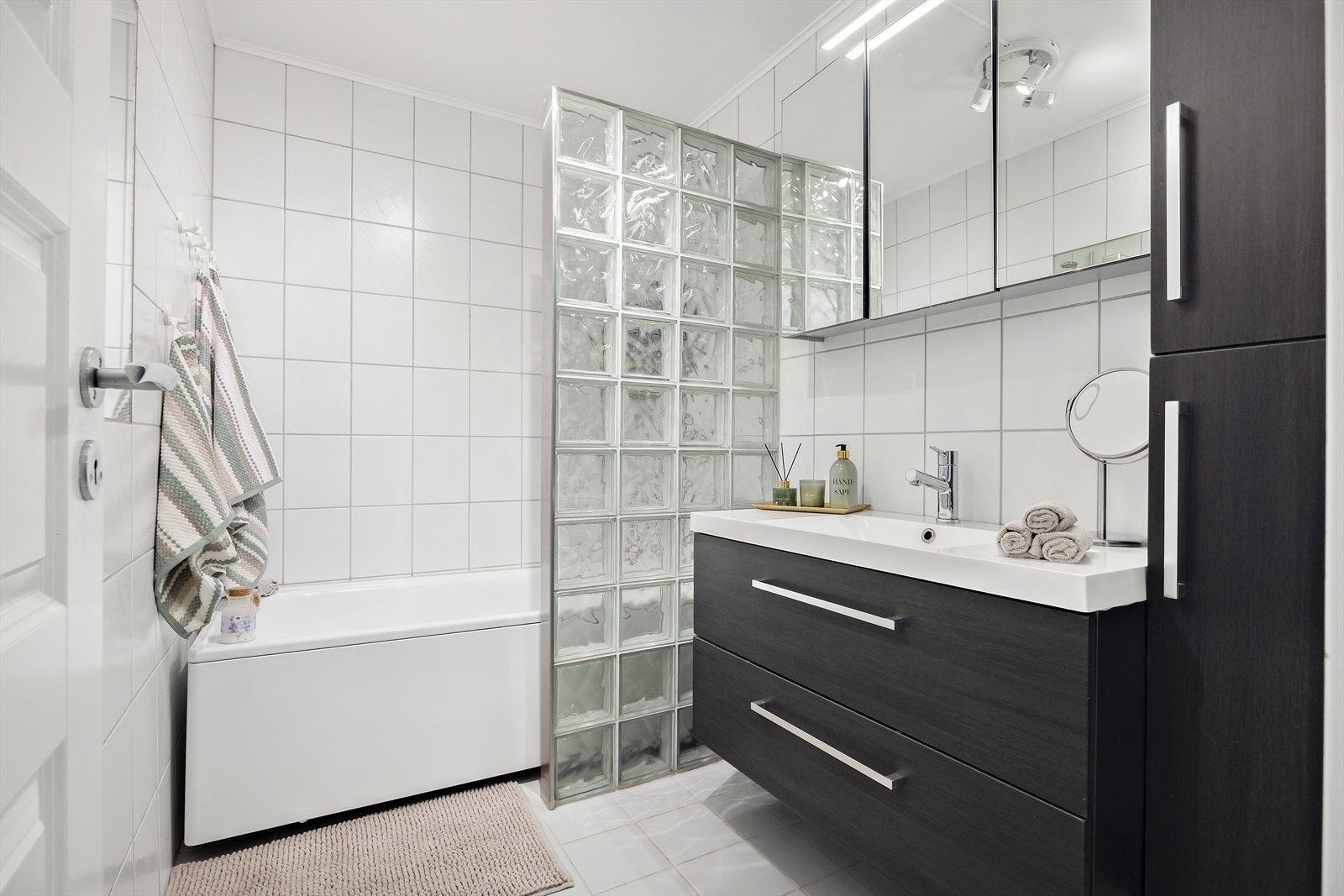 Badet er flislagt med varme i gulvet og har servantskap med glatte, folierte fronter Galleribilde