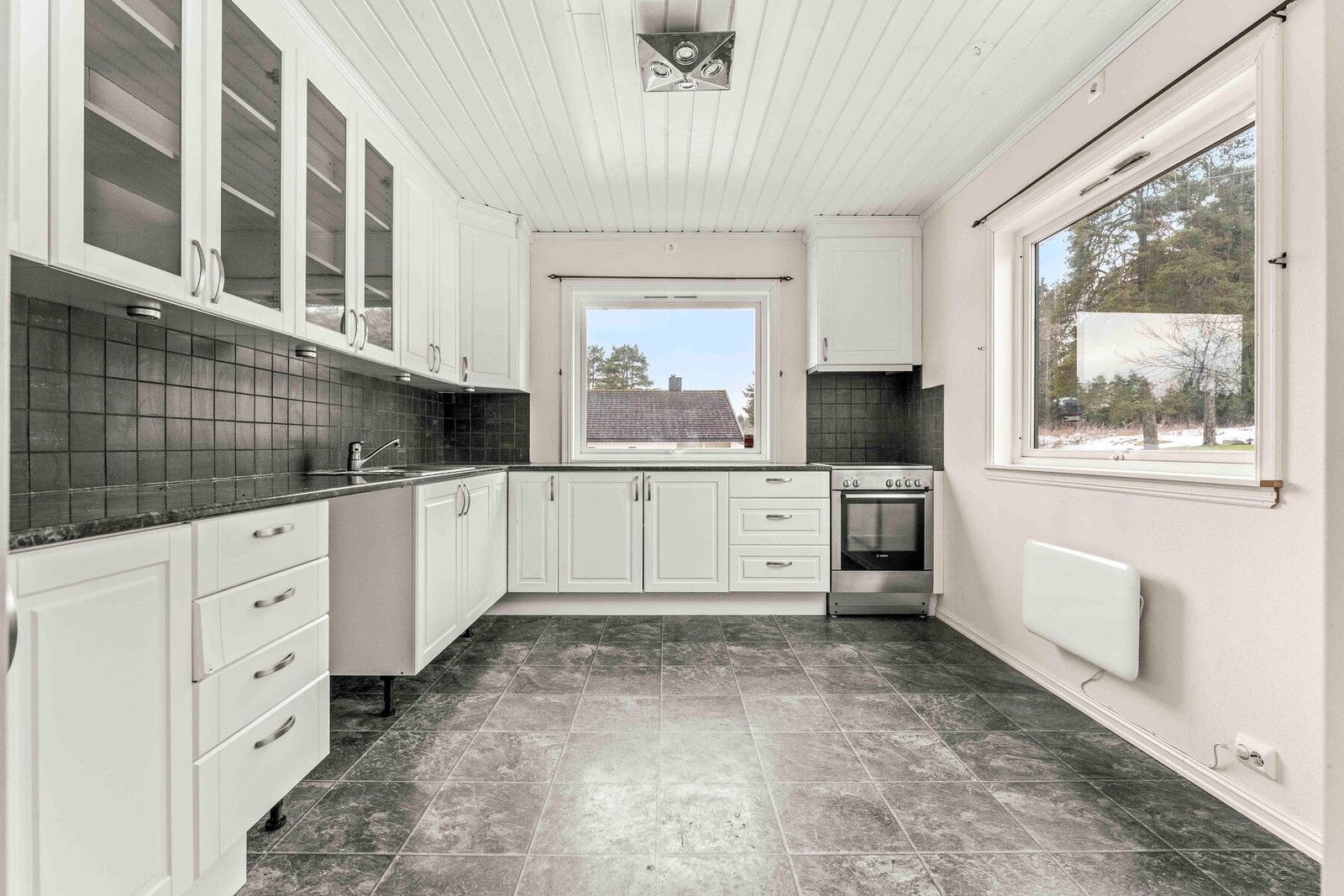 Lyst og romslig kjøkken med rikelig skap - og benkeplass. Plass til et frokostbord for familien Galleribilde