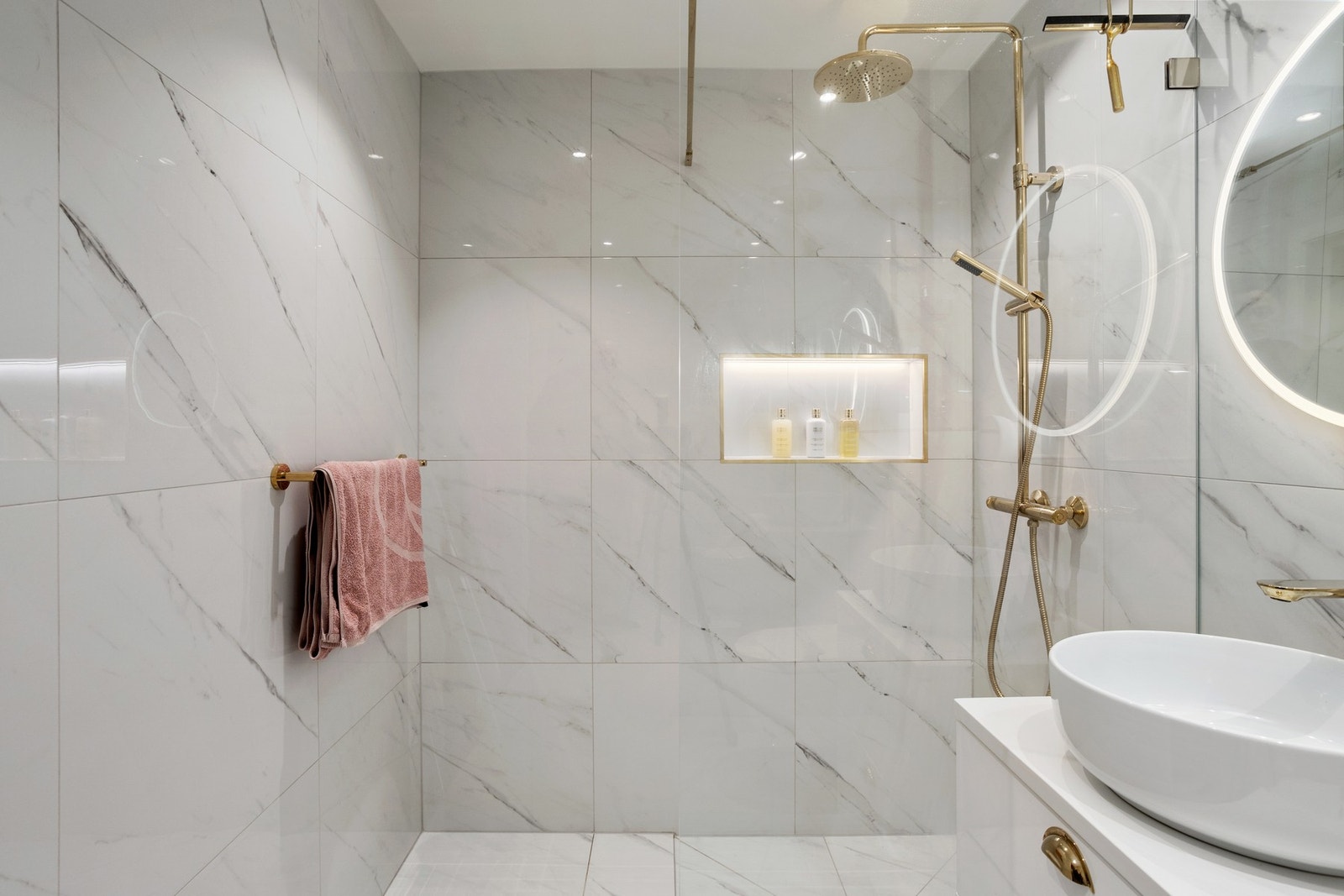 Badet har marmorerte fliser på vegger og gulv, varmekabler og delikate detaljer i gullfarge. Galleribilde