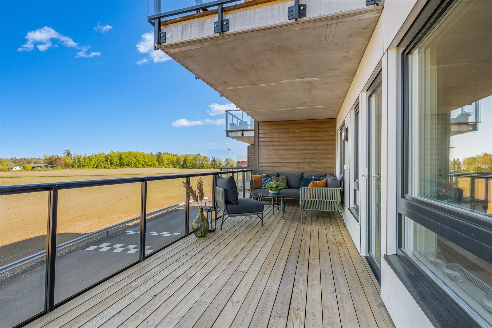 Utgang fra stue til 18 m2 balkong i betong, med oppforet impregnert tregulv. Flott glassrekkverk som ivaretar utsikten. Dels overbygd tak i betong. Galleribilde