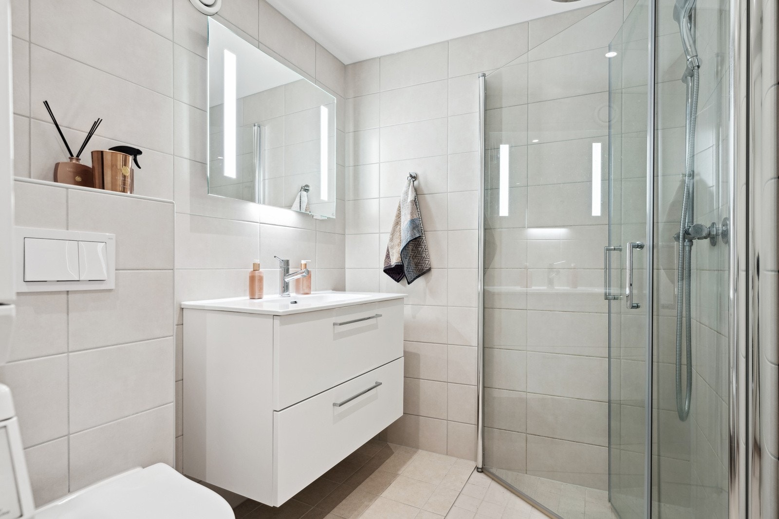 Badet inneholder veggmontert innredning med heldekkende servant og ett-greps armatur, seil over servant med belysning og stikkontakt,dusjnisje med glassdører og ett-greps dusjarmatur. Vegghengt toalett. Opplegg for vaskemaskin. Galleribilde