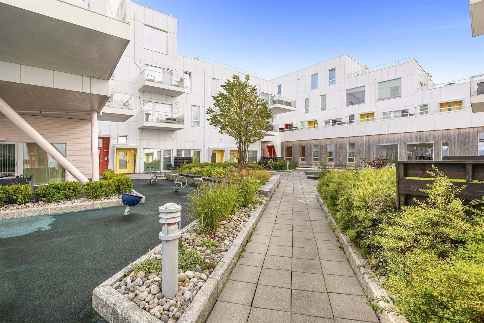 Fellesarealet er pent opparbeidet med belegningsstein, busker og trær, samt lekeplass Galleribilde