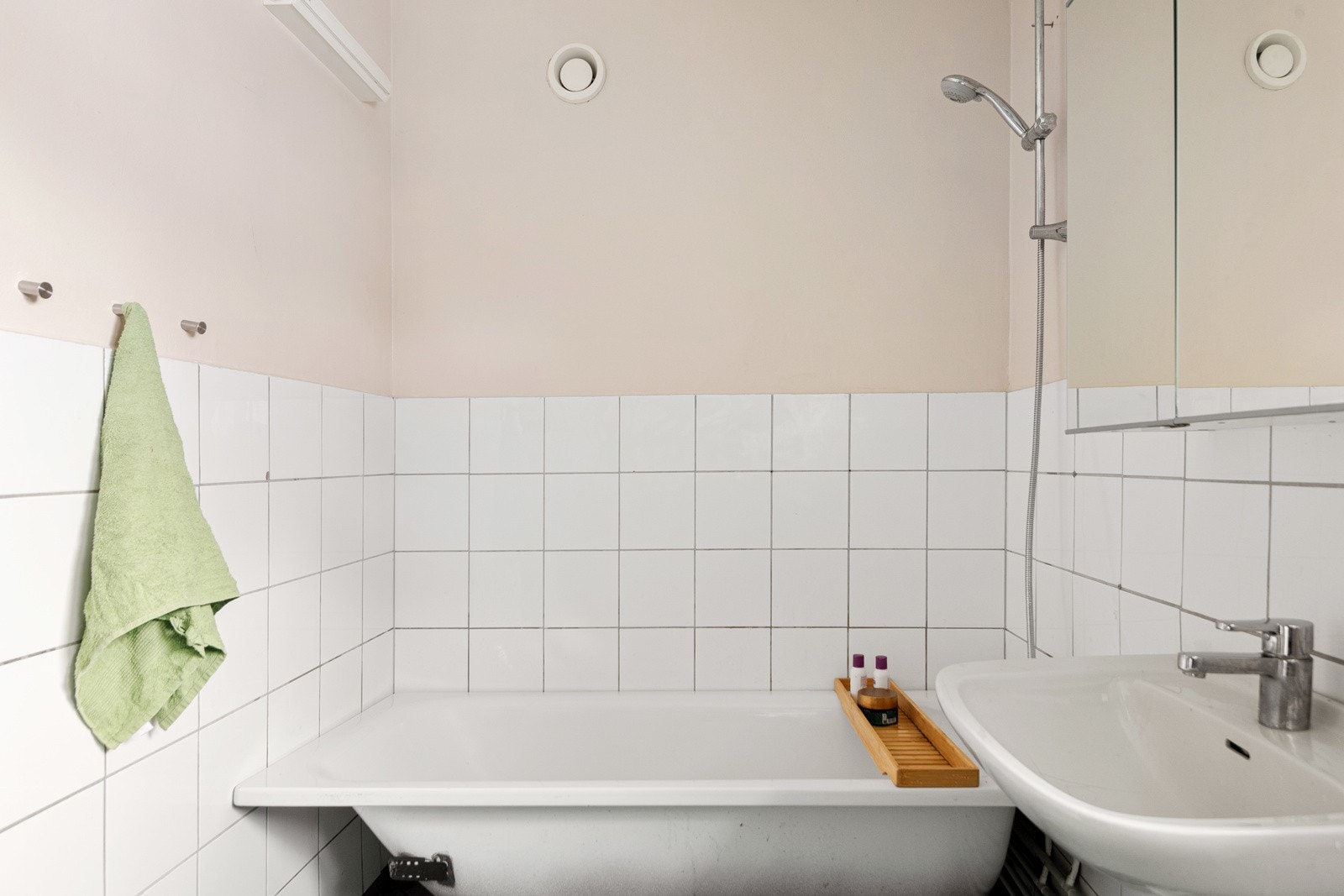 Badet er utstyrt med badekar med dusj, servant med speil over, flislagt gulv og delvis vegger Galleribilde