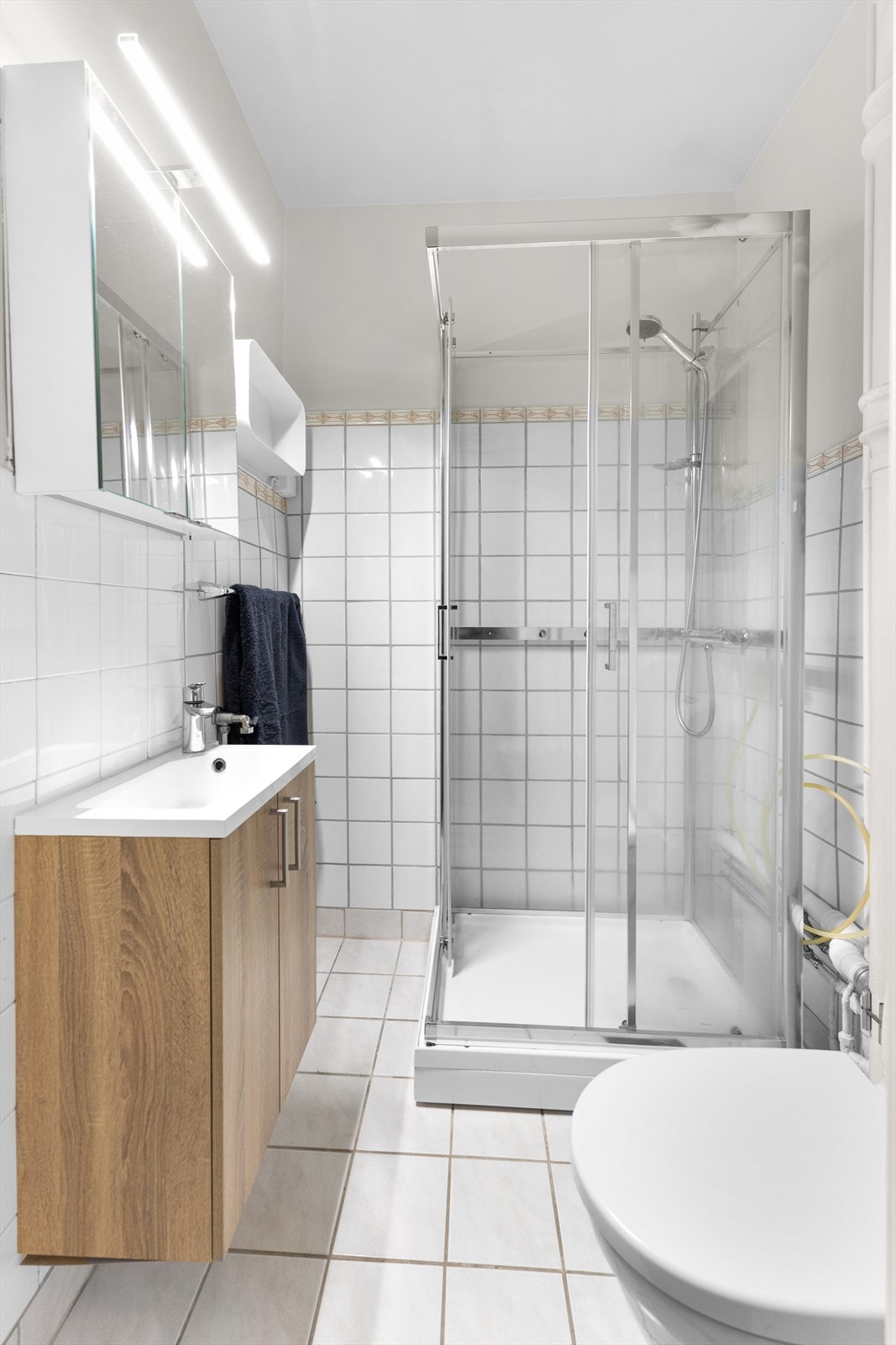 Flislagt bad innredet med nytt dusjkabinett 2024. Gulvstående klosett, servant og opplegg for vaskemaskin. Galleribilde