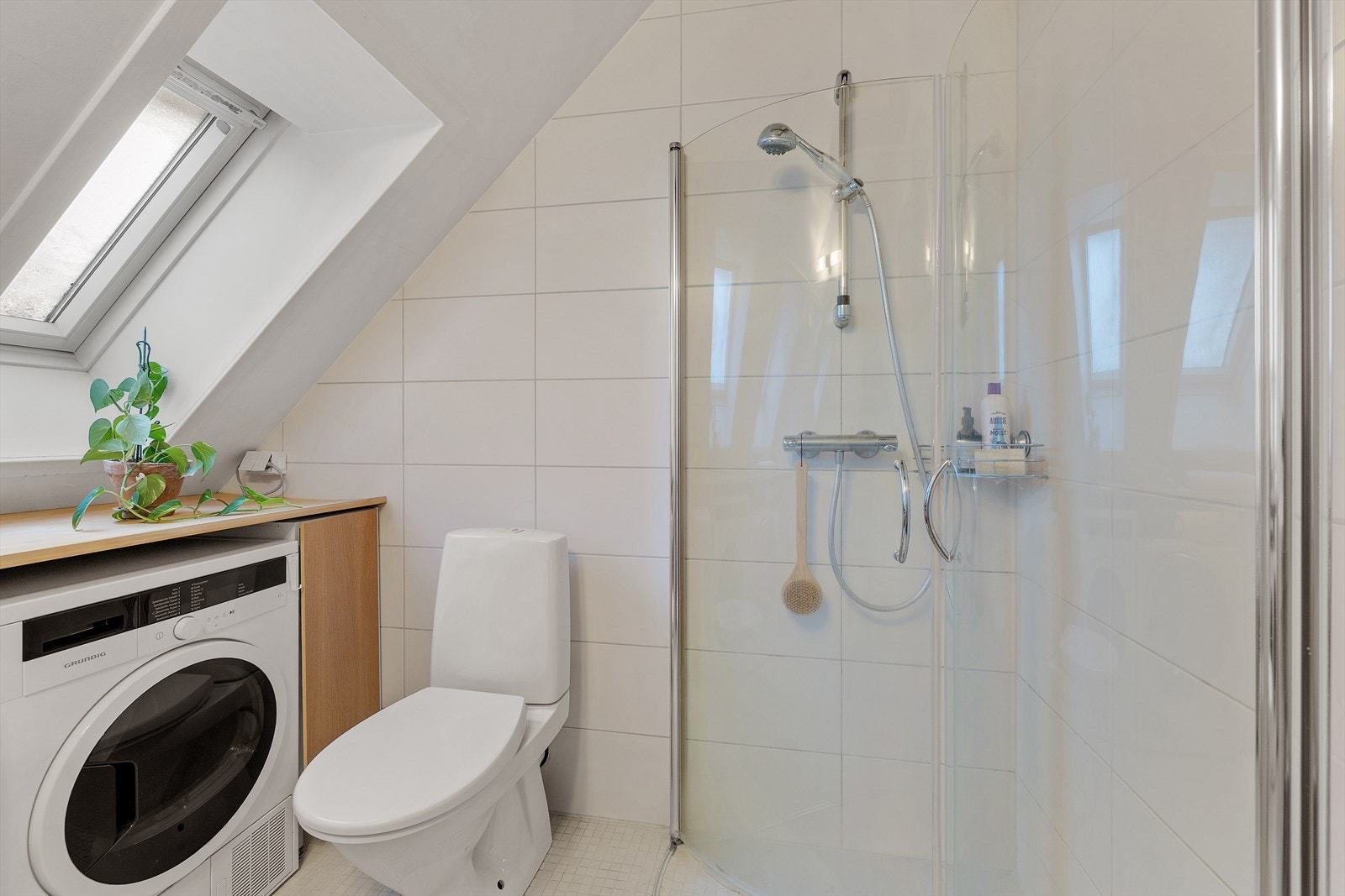 Badet inneholder et frittstående toalett og servant med speil og lys. Det er også opplegg for vaskemaskin og plass til tørketrommel. Galleribilde