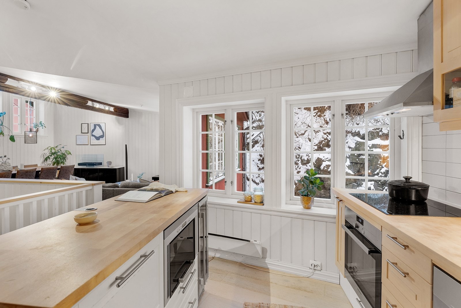 Avtrekksvifte over induksjonstopp. Kjøkkenet er utstyrt med integrert komfyr samt frittstående oppvaskmaskin og kjøl/ frys. Galleribilde