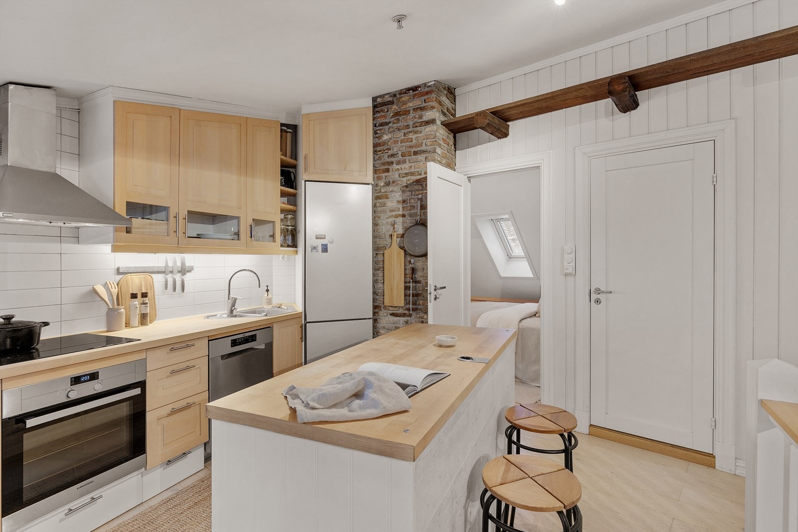 Pen kjøkkeninnredning med 1-speils fronter i bjørk, heltre benkeplate og fliser i benkerygg. Galleribilde