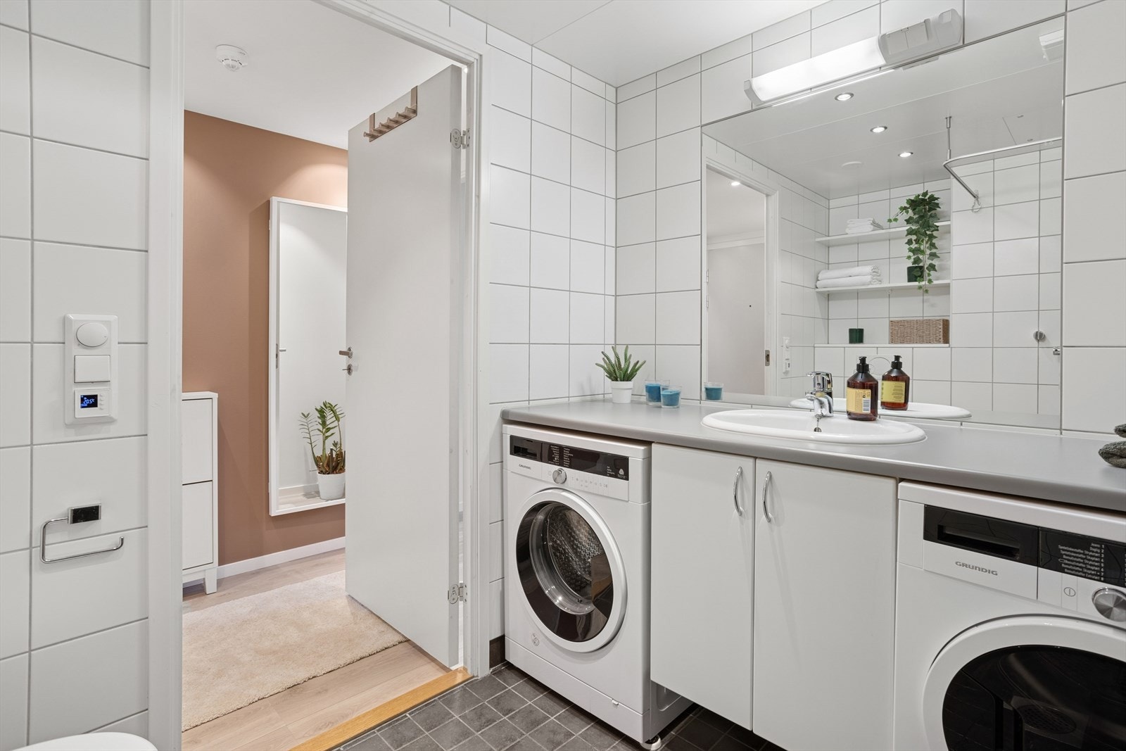 Badet inneholder vegghengt toalett, dusj, nedfelt servant med underskap og speil m/belysning, benkeplaten er i laminat og over toalettet er det innebygde hyller. Galleribilde