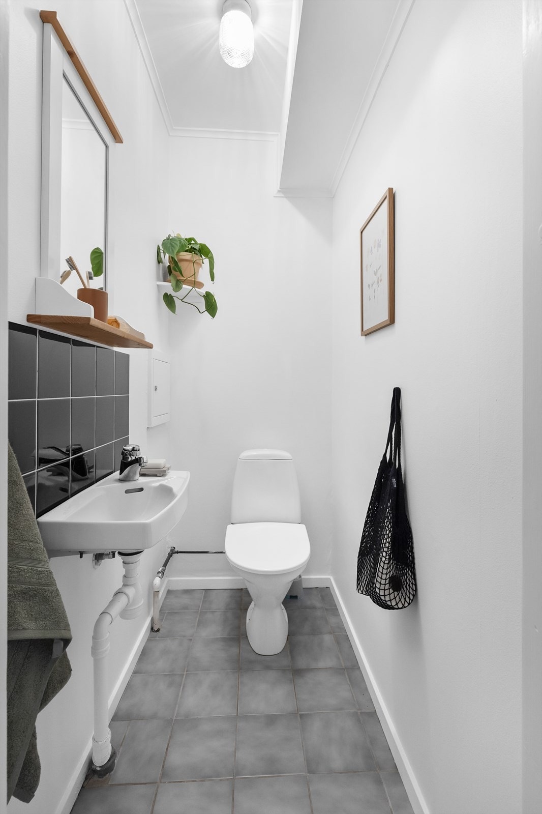 Videre er boligens toalett avholdt i et delikat, separat toalettrom, som er innredet med frittstående toalett og servant med overhengt speil. Galleribilde