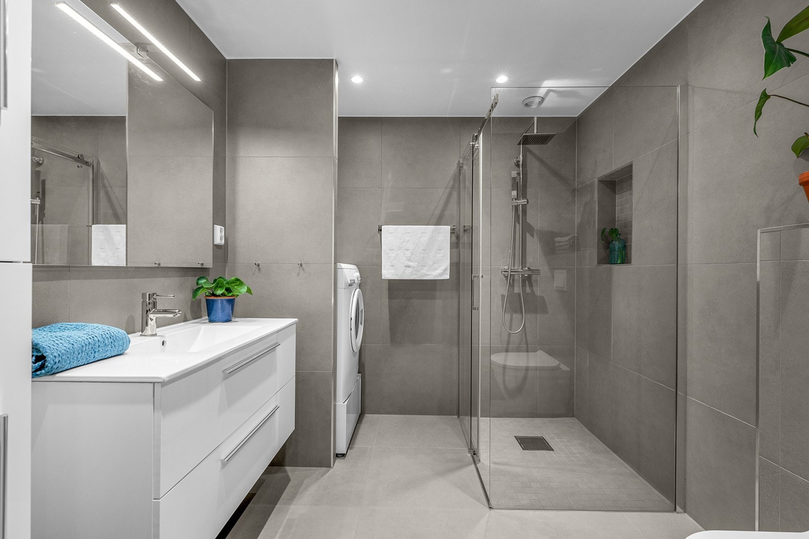 Lekkert og delikat baderom (2018) med store fliser på gulv og vegg. Flott og romslig dusjsone med glassvegger, samt både regnfallsdusj og hånddusj. Galleribilde