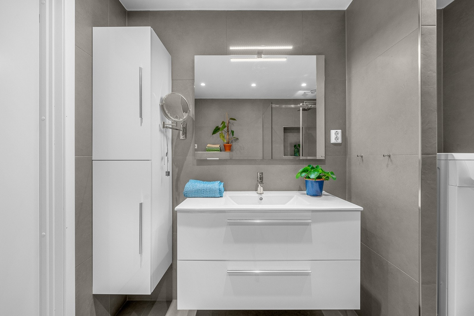 Moderne hvit innredning med skuffer og heldekkende servant, speil og belysning. Videre har badet gulvvarme, vegghengt vannklosett, opplegg for vaskemaskin og downlights i himling. Galleribilde