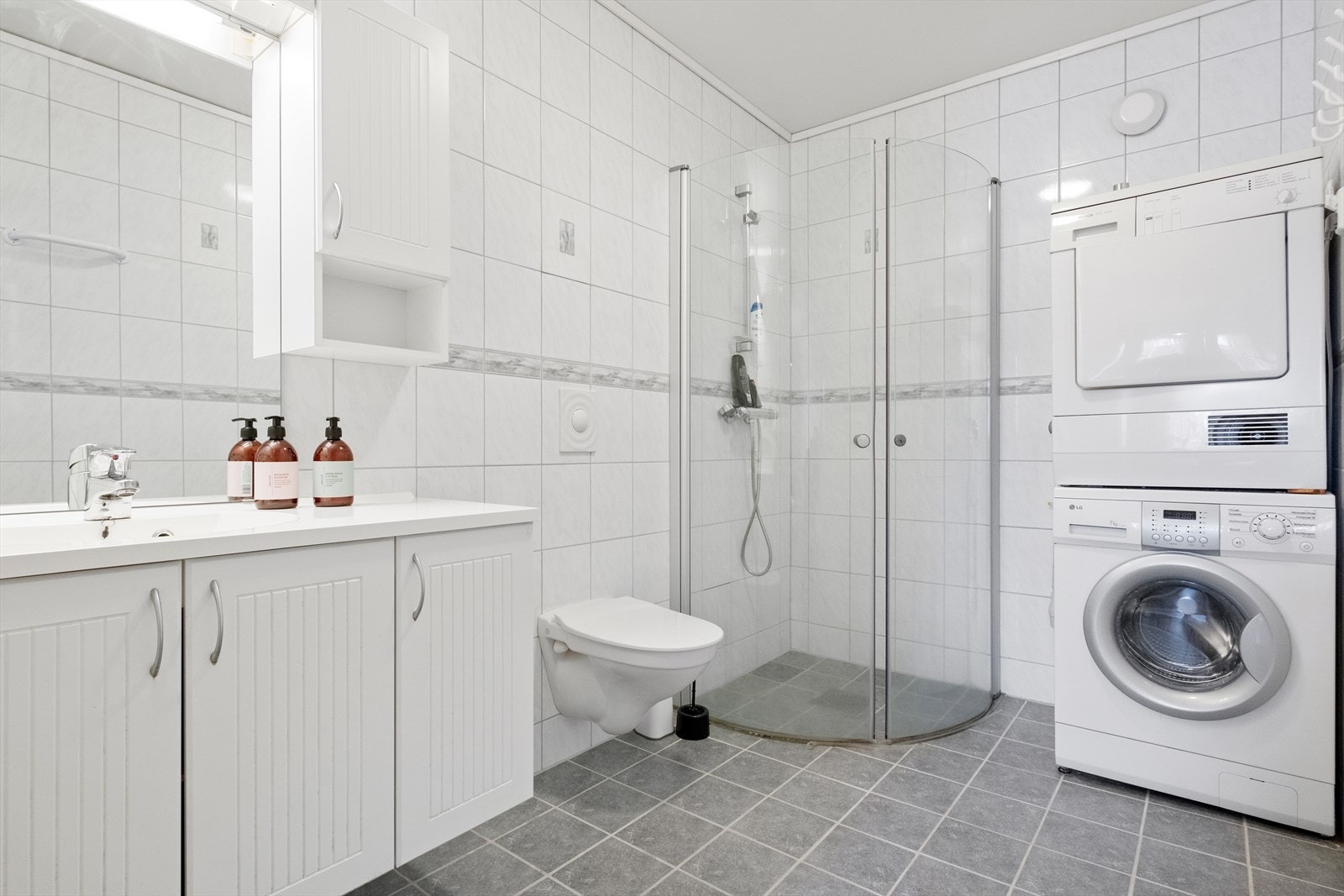 Dusjhjørne med glassvegger. Det er opplegg for vaskemaskin på badet Galleribilde