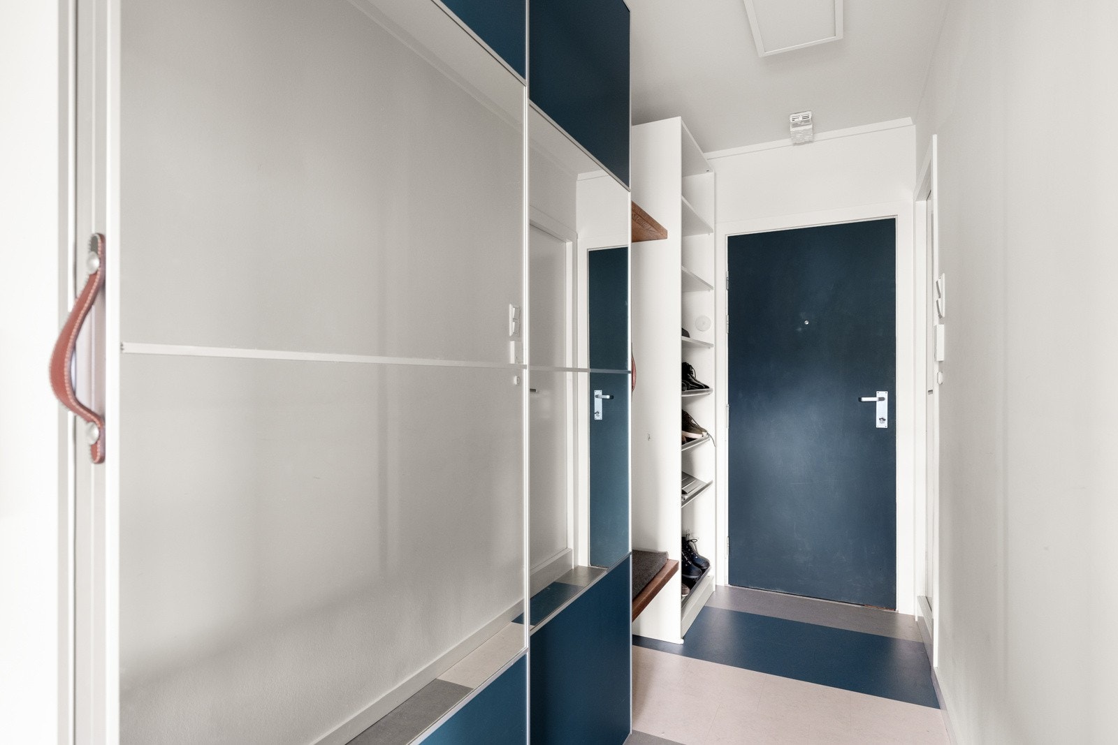 Gangen er innredet med hvitmalte vegger og grå laminatfliser på gulvet. Jakker og annet yttertøy ryddes enkelt bort i en stor skyvedørsgarderobe med dels speilfronter Galleribilde