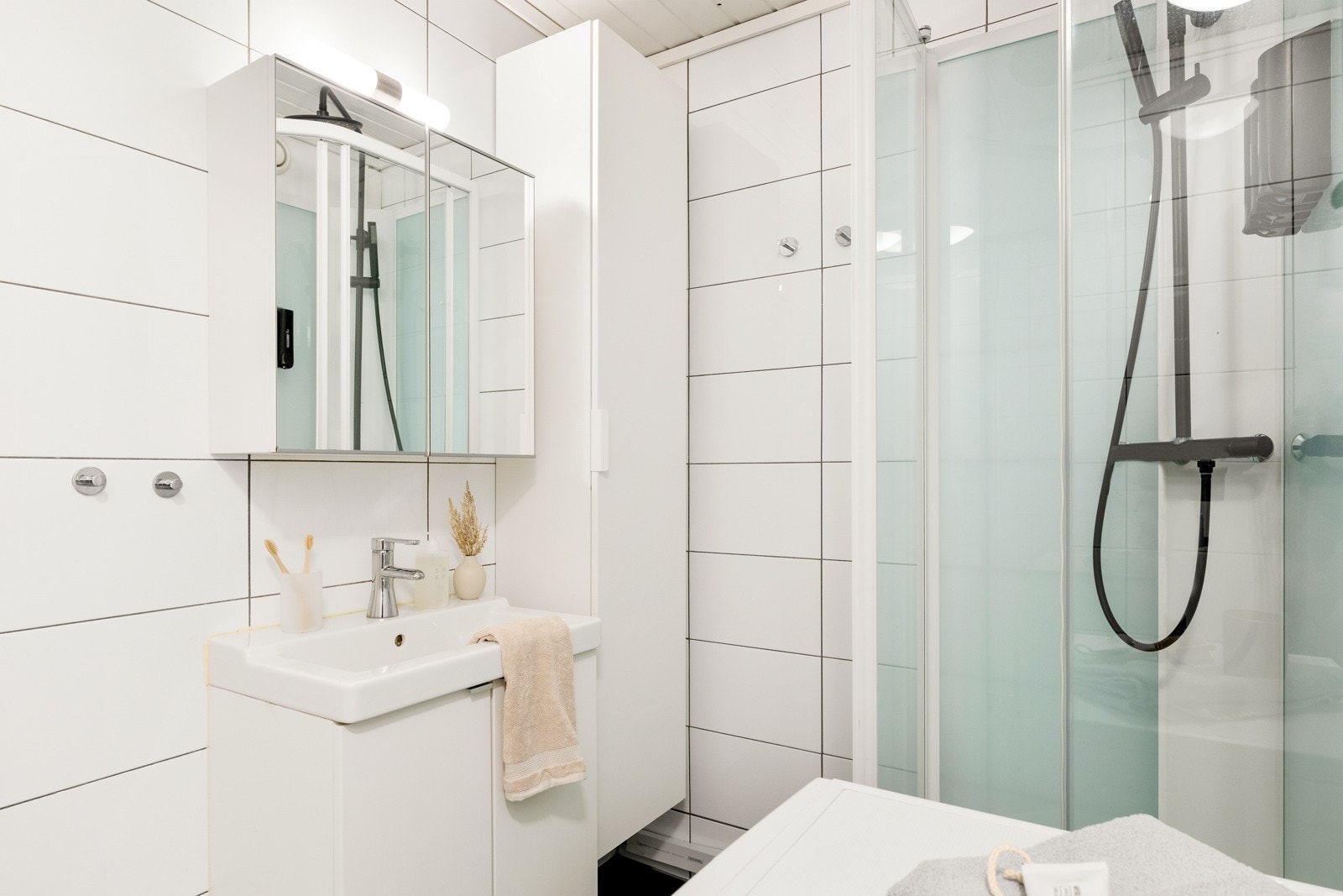 Opplegg for vaskemaskin er etablert, og på badet er det toalett, varmekabler og et dusjkabinett med sort regnfallsdusj Galleribilde