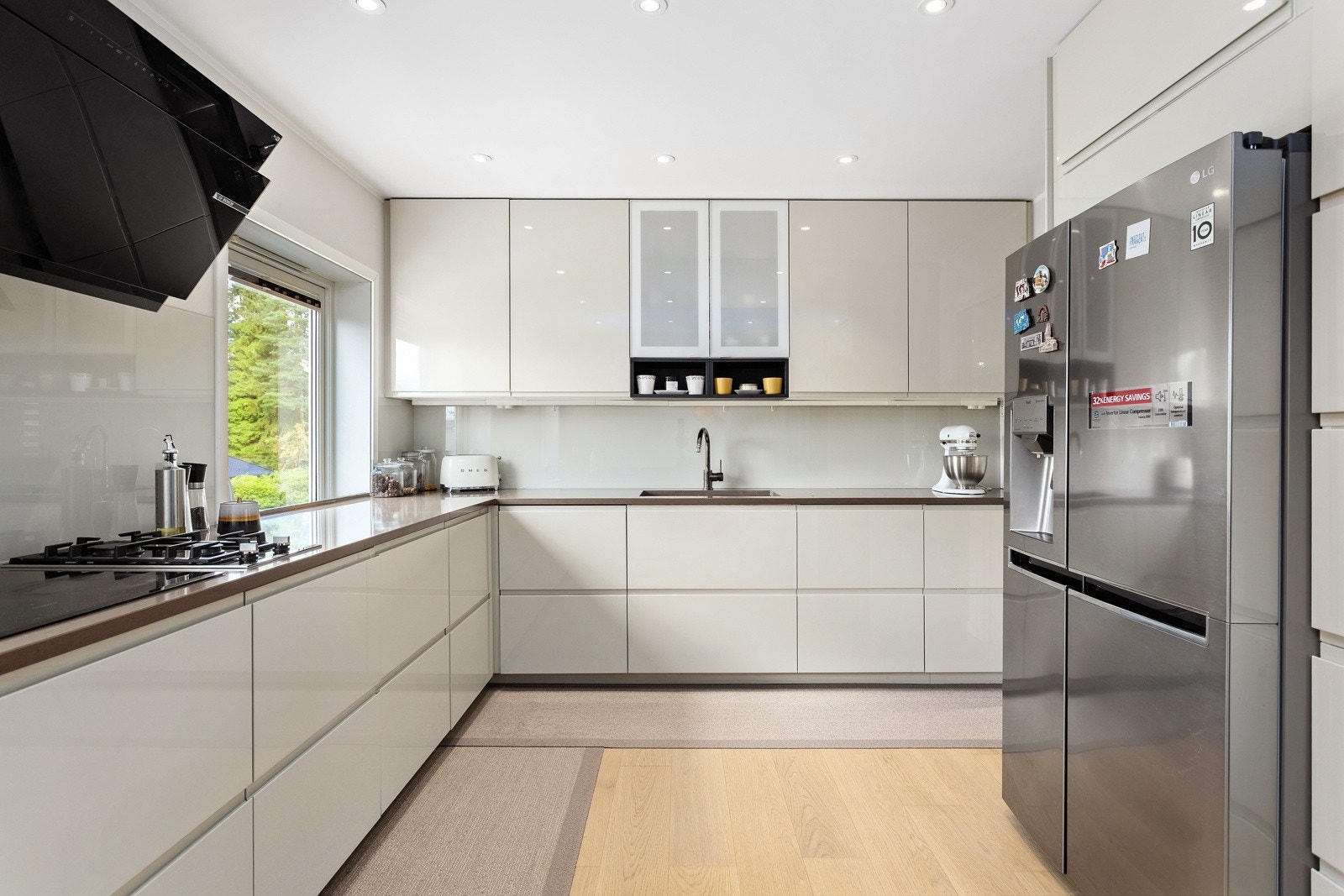 Kjøkkeninnredning med glatte fronter og benkeplate av stein/kompositt. Galleribilde