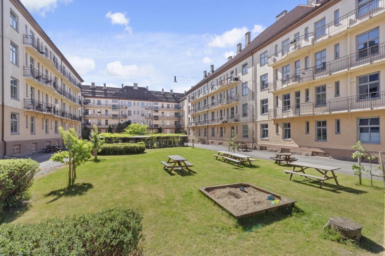 Bakgården på sommertid med stor boltreplass, benker, griller og mulighet for sosiale sammenkomster. Galleribilde