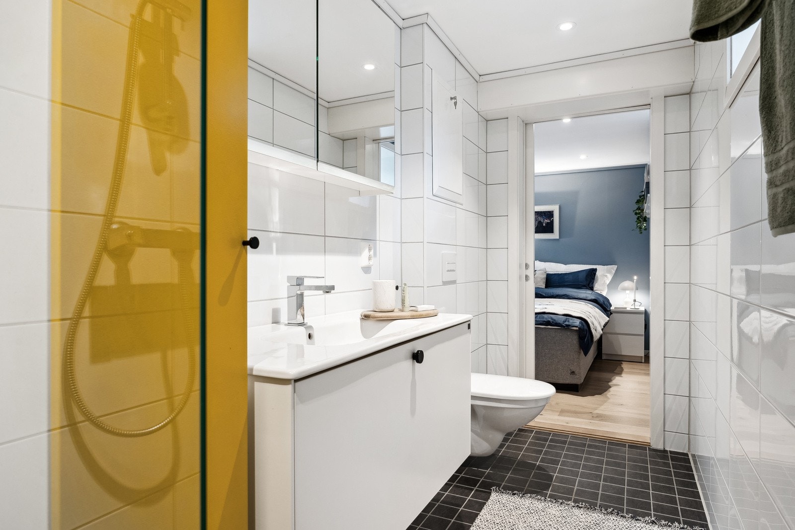 Badet er utstyrt med servantinnredning, skap, speilskap, dusjhjørne og vegghengt toalett. Galleribilde