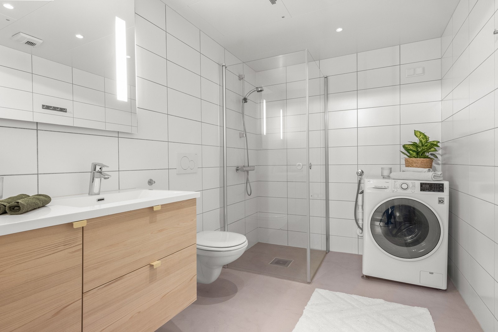 Videre har badet vegghengt klosett, servant nedfelt i praktisk og god innredning, speilskap med integrert belysning og et dusjhjørne med svingbare glassdører. Det er plass og opplegg for vaskemaskin i søyle. Galleribilde