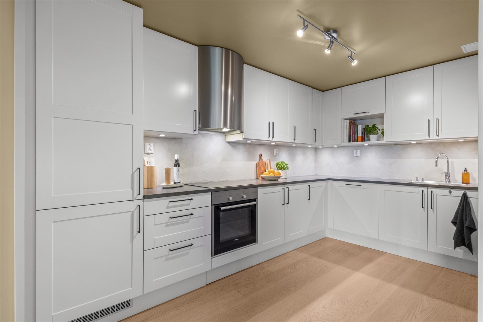 Kjøkkenet har glatte fronter og en laminatbenkeplate med nedfelt vask. Kjøkkenet er godt utstyrt med integrert platetopp (2022) stekeovn, oppvaskmaskin (2023) og kjøl/fryseskap. Det er avtrekk over kokeplassen for optimal ventilasjon. Galleribilde