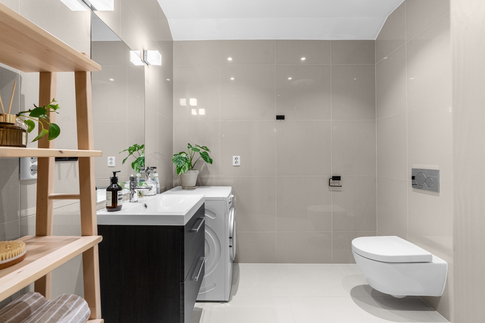 Badet ble etablert i 2015 og har et stilrent uttrykk med store fliser i moderne beigetoner. Flisene på gulvet ble lagt i 2023. Galleribilde