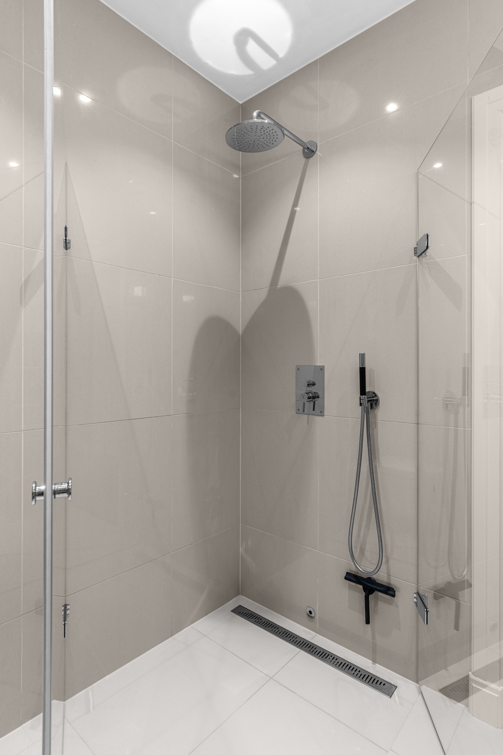 Dusjhjørnet er utstyrt med slukrenne, regnfallsdusj, hånddusj, og innfellbare glassdører. Galleribilde