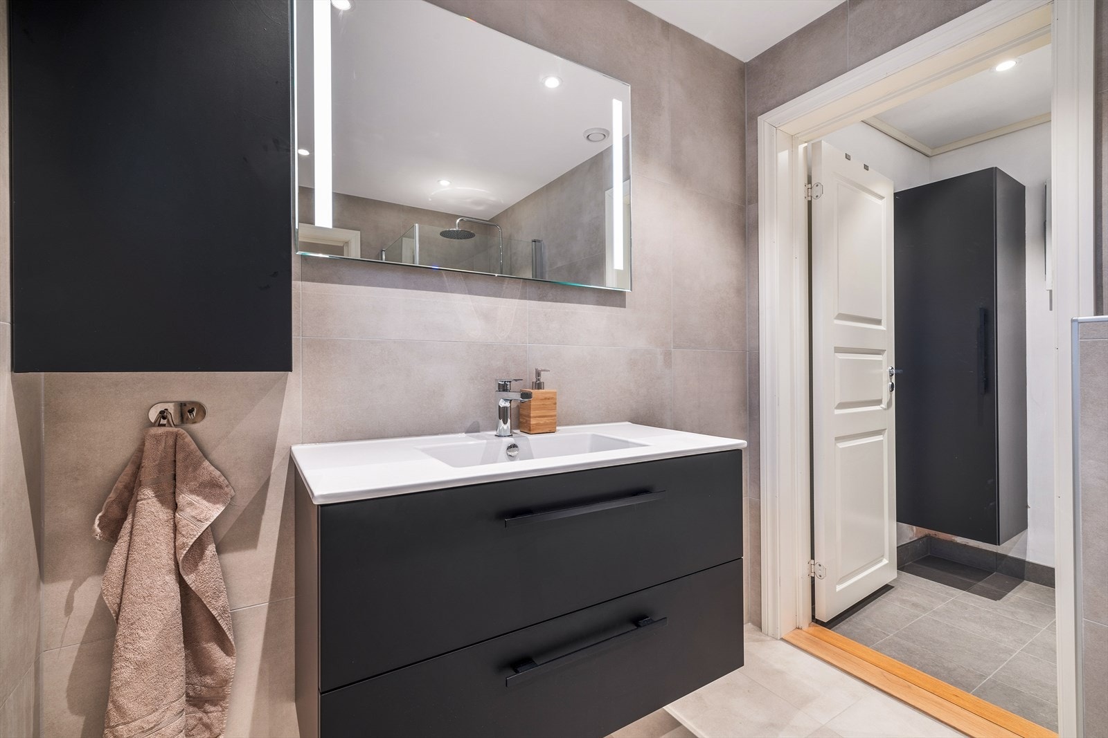 Moderne og stilrent bad med romslig servant og praktisk oppbevaring. Et innbydende rom for avslapning og velvære. Galleribilde